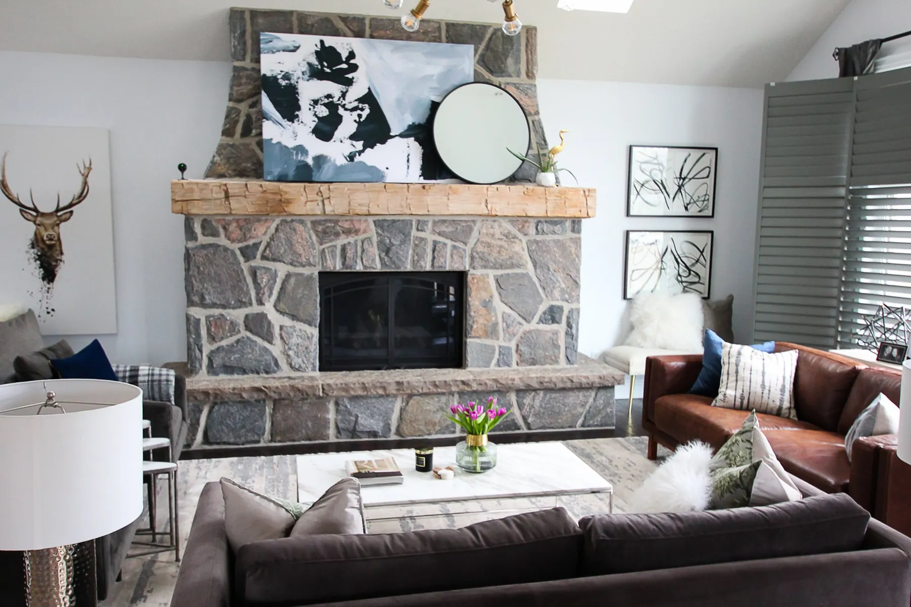 Family room with a stone fireplace by White Dahlia Design