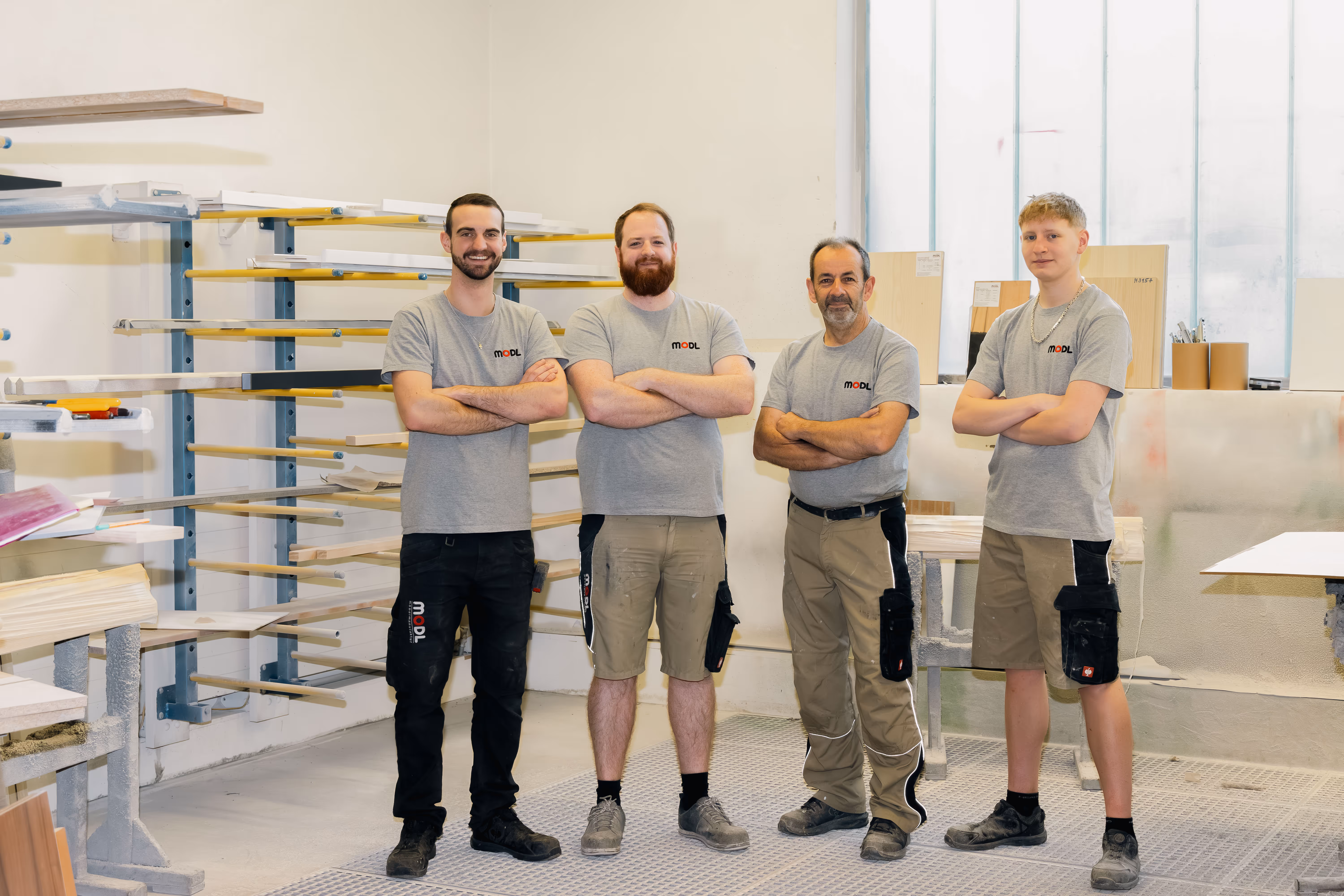 Drei Männer mit Arbeitsoutfit in einer Werkstatt