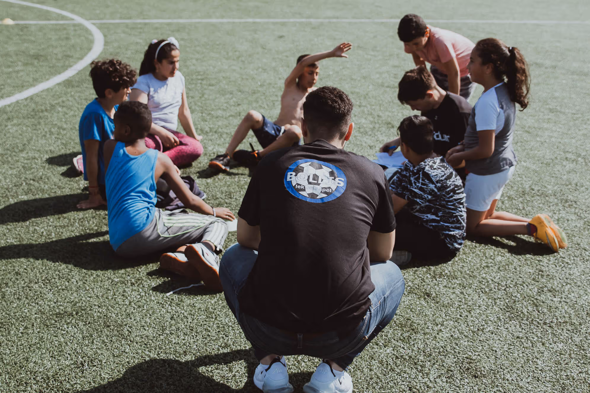 An image depicting two coaches having a team meeting with seven children.