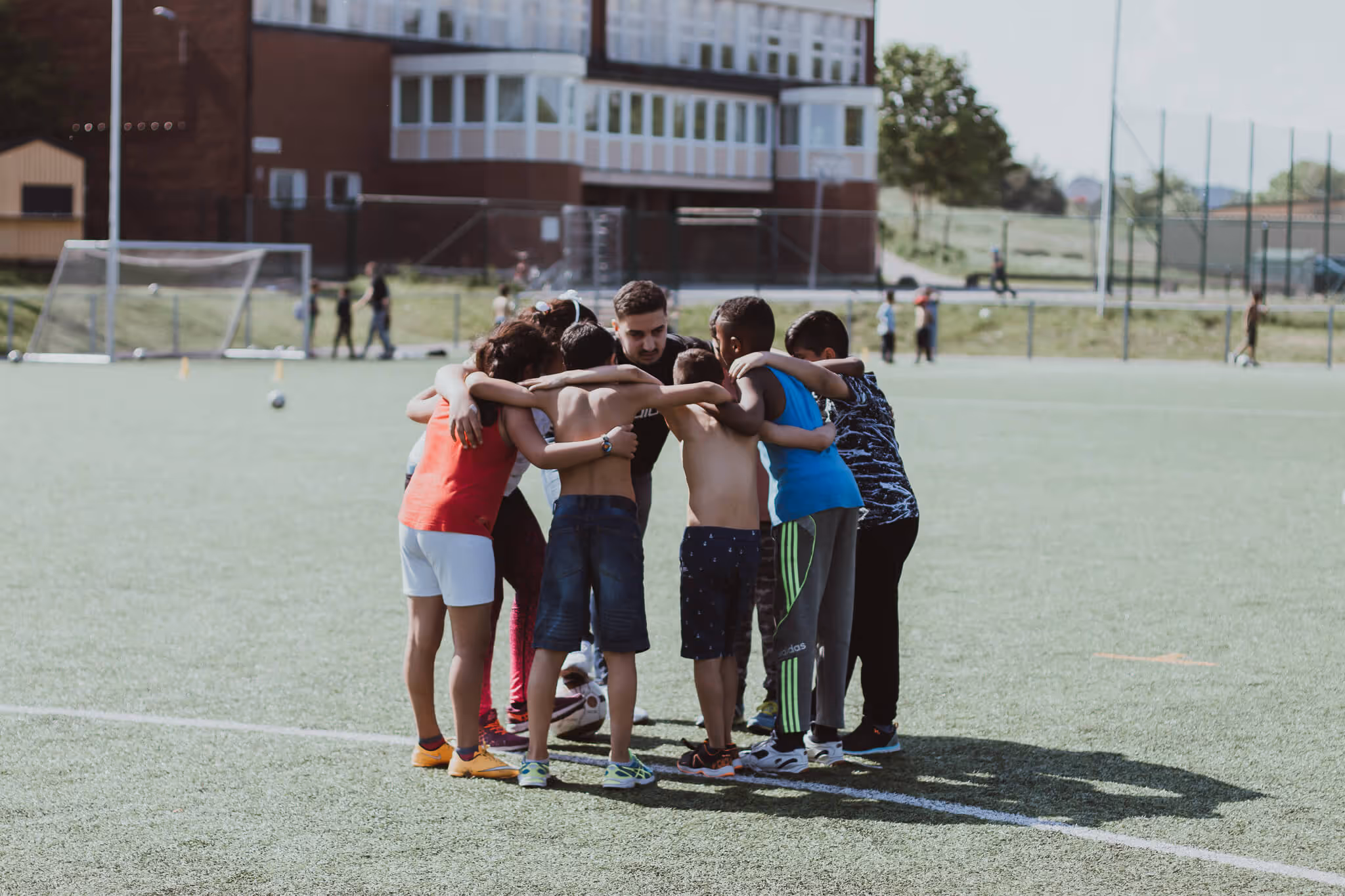An image depicting a coach having a team meeting with seven children.