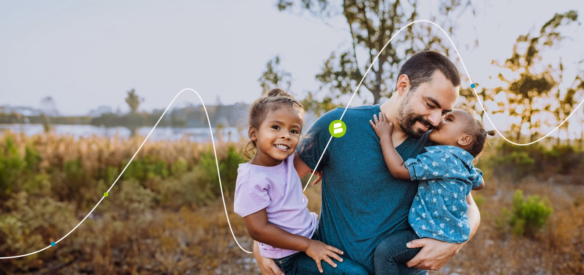 Man holding a baby outdoors with a young girl beside him
