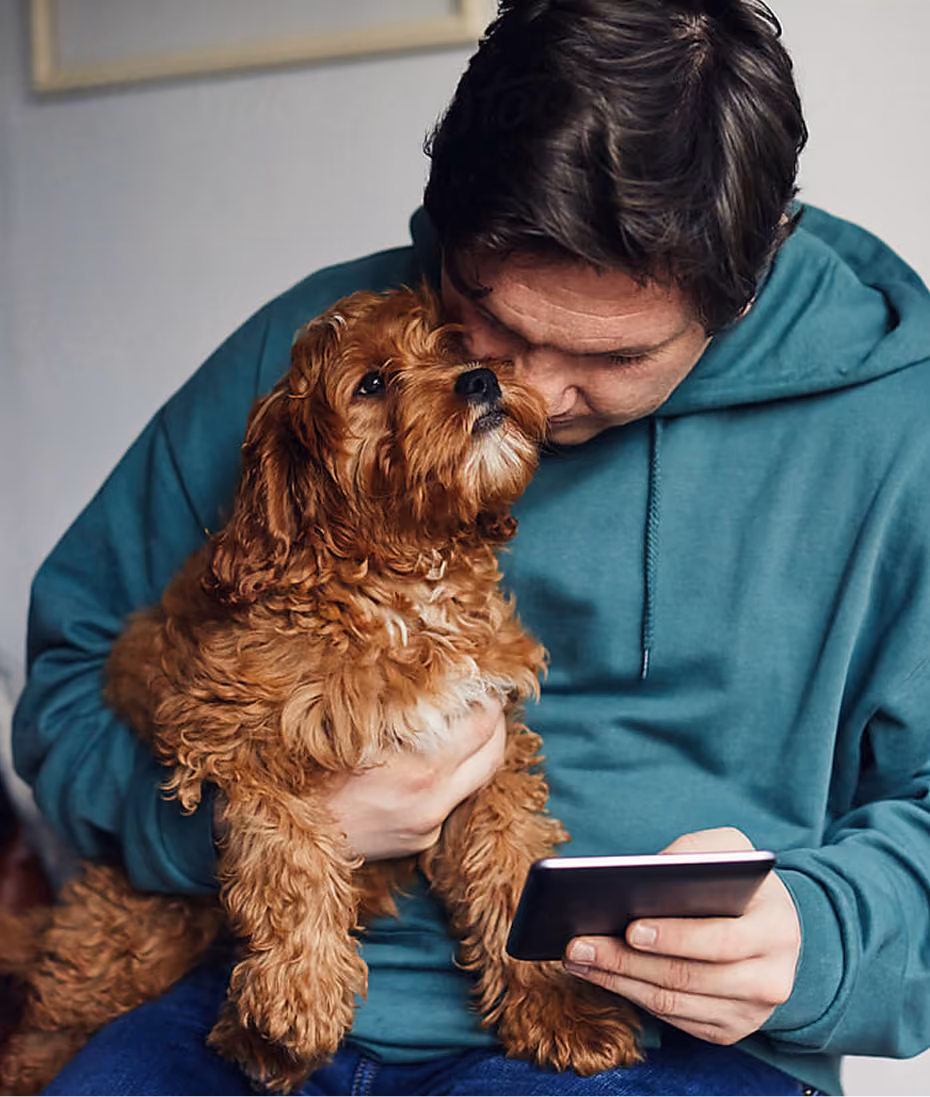 Man holding a small curly-haired dog close to his face