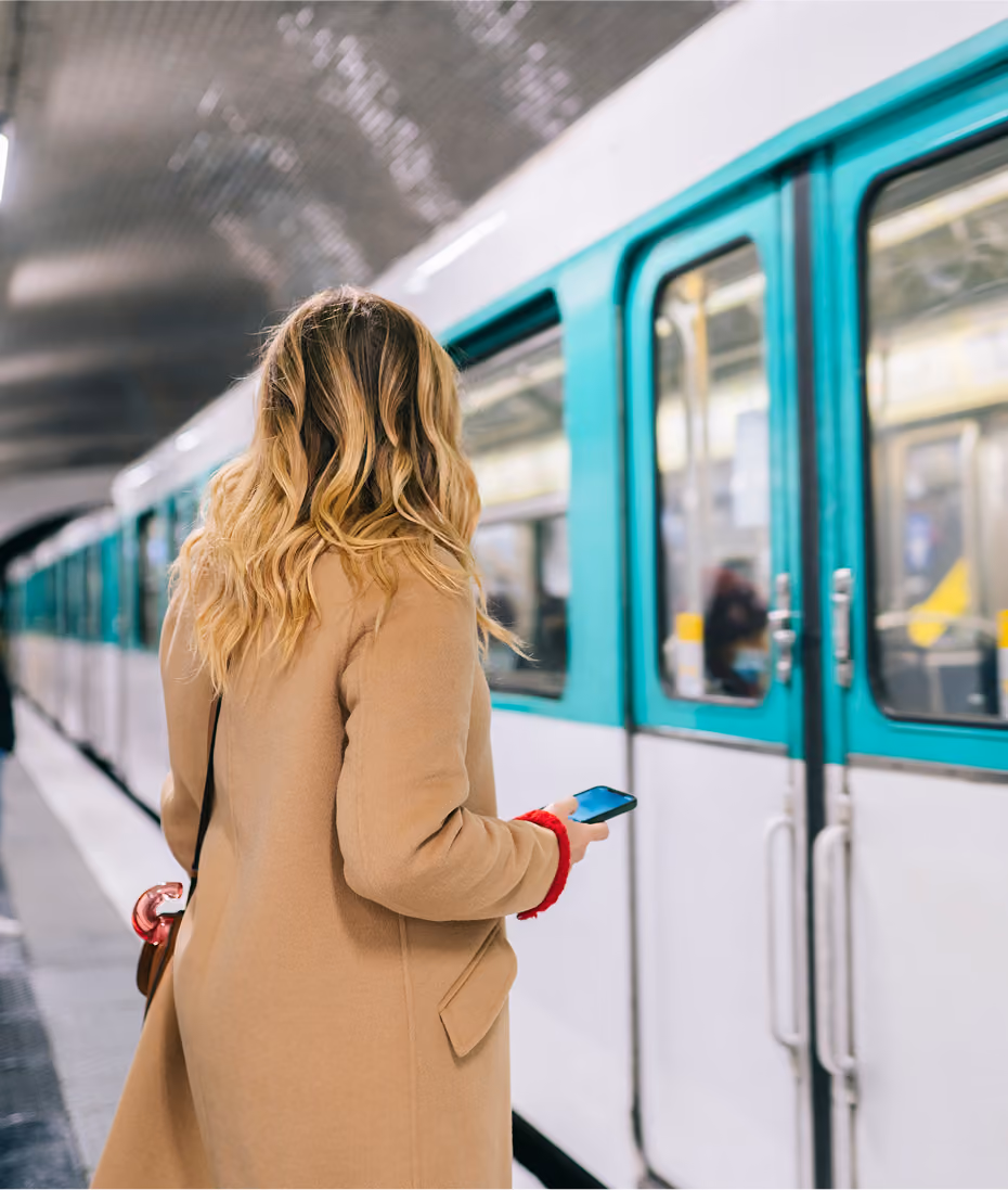 Woman holding a phone as she steps toward a train at a platform
