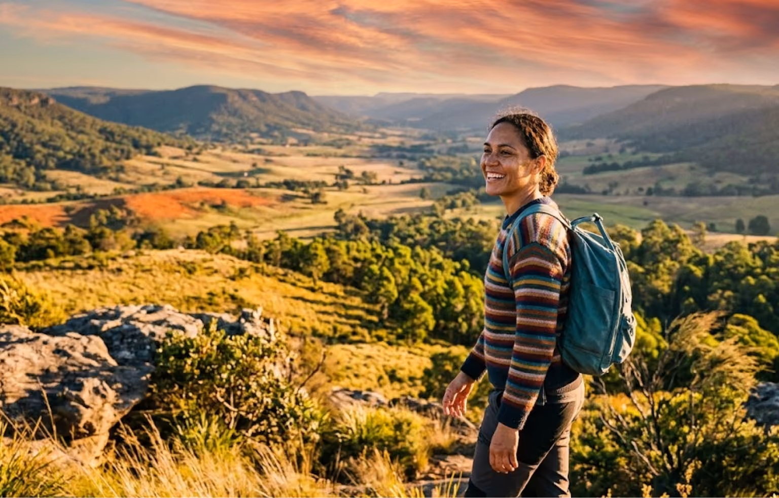 Woman with a backpack pausing on a hilltop above a valley