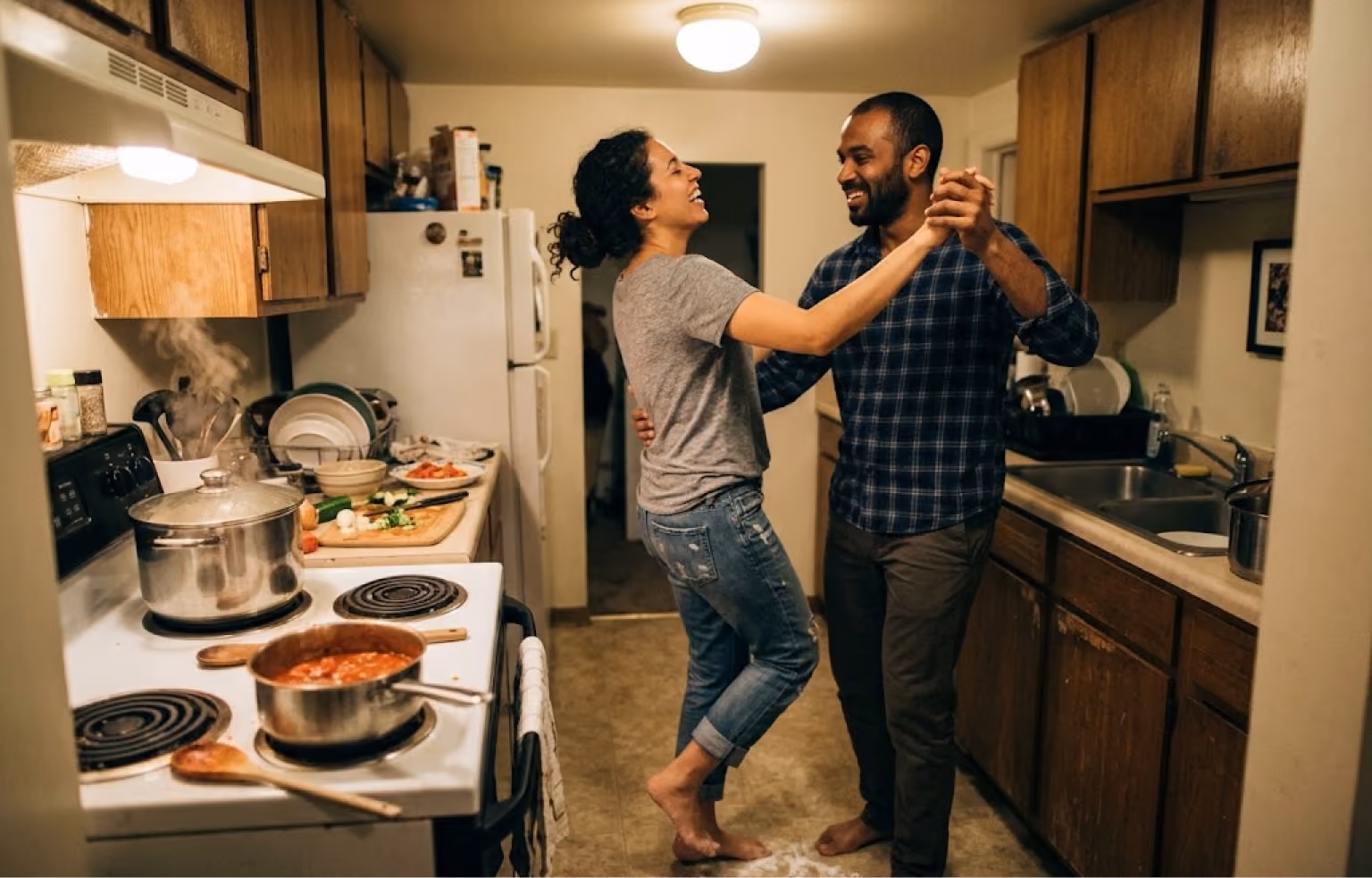 Couple dancing in their kitchen while dinner cooks on the stove