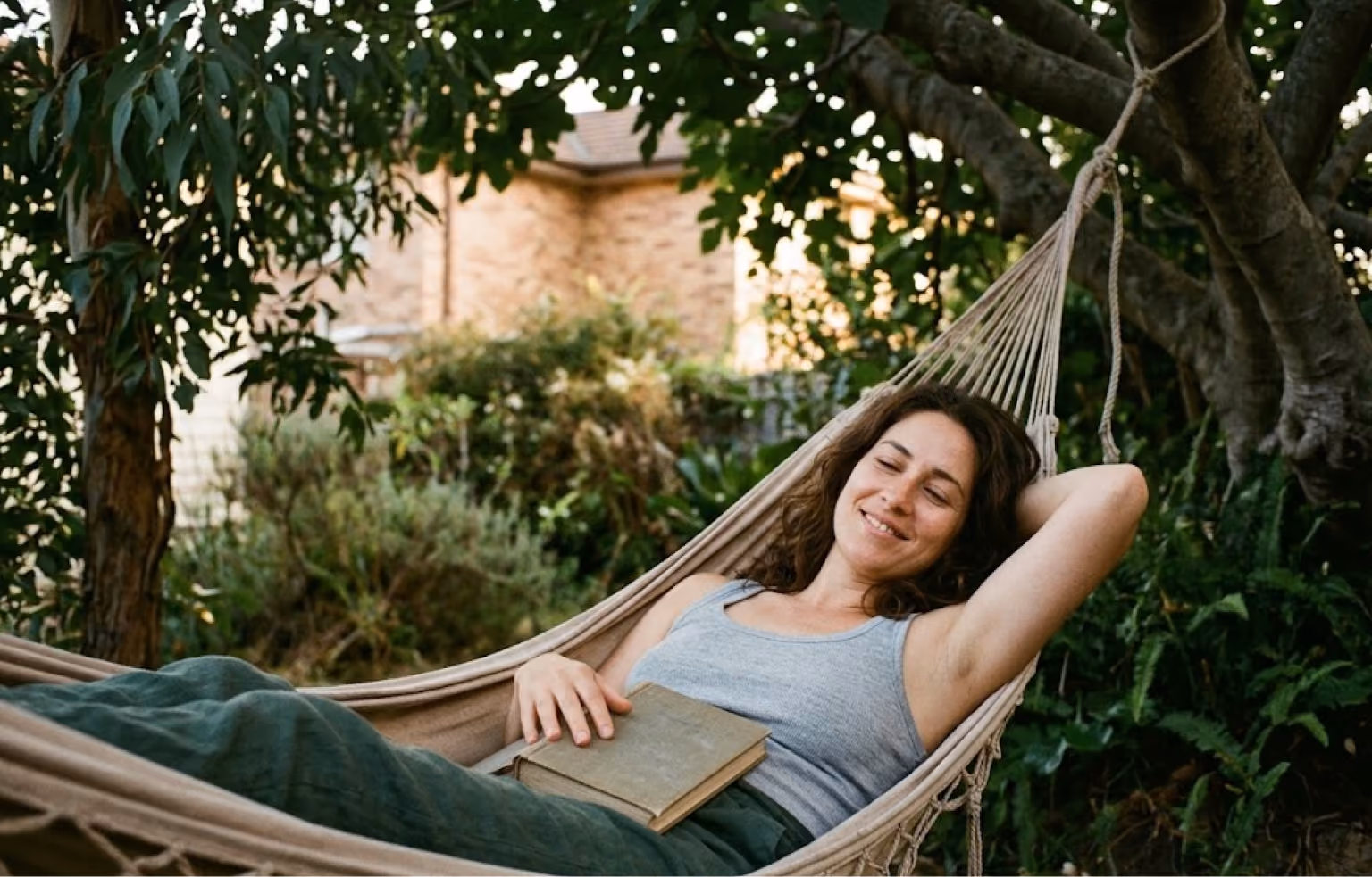 Woman resting in a garden hammock with a book
