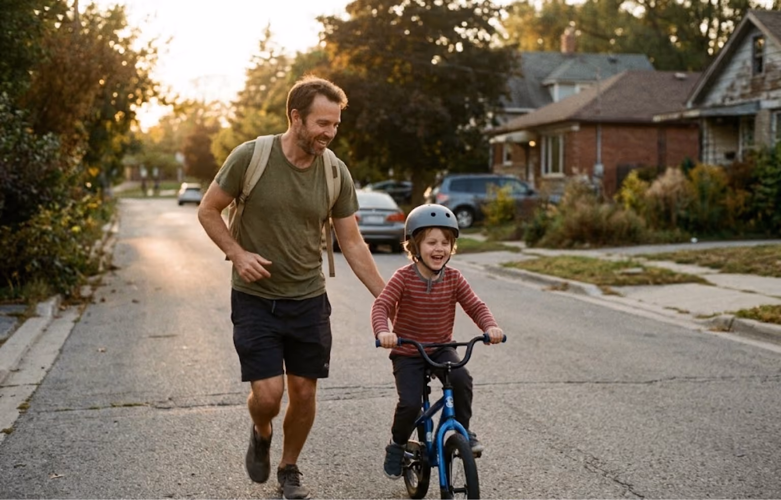 Man jogging beside a young boy learning to ride a bike