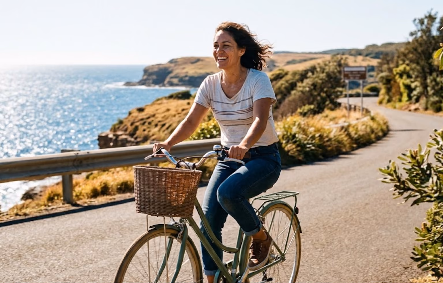 Woman riding a bicycle along a coastal road
