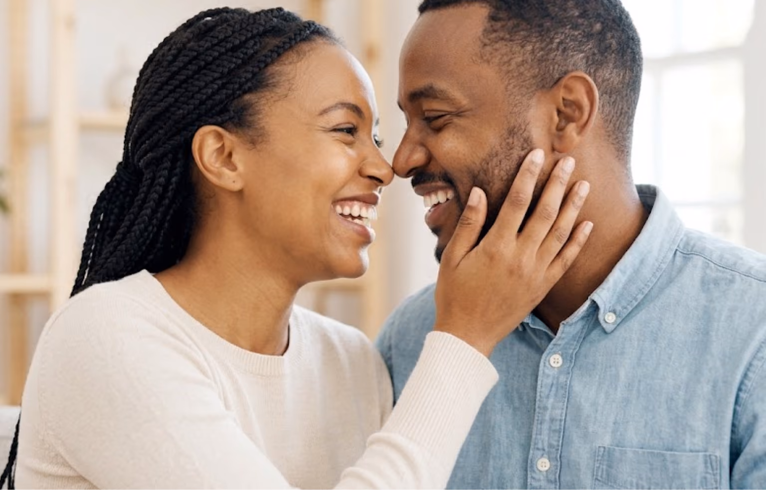 Smiling couple standing close, the woman's hand on the man's cheek