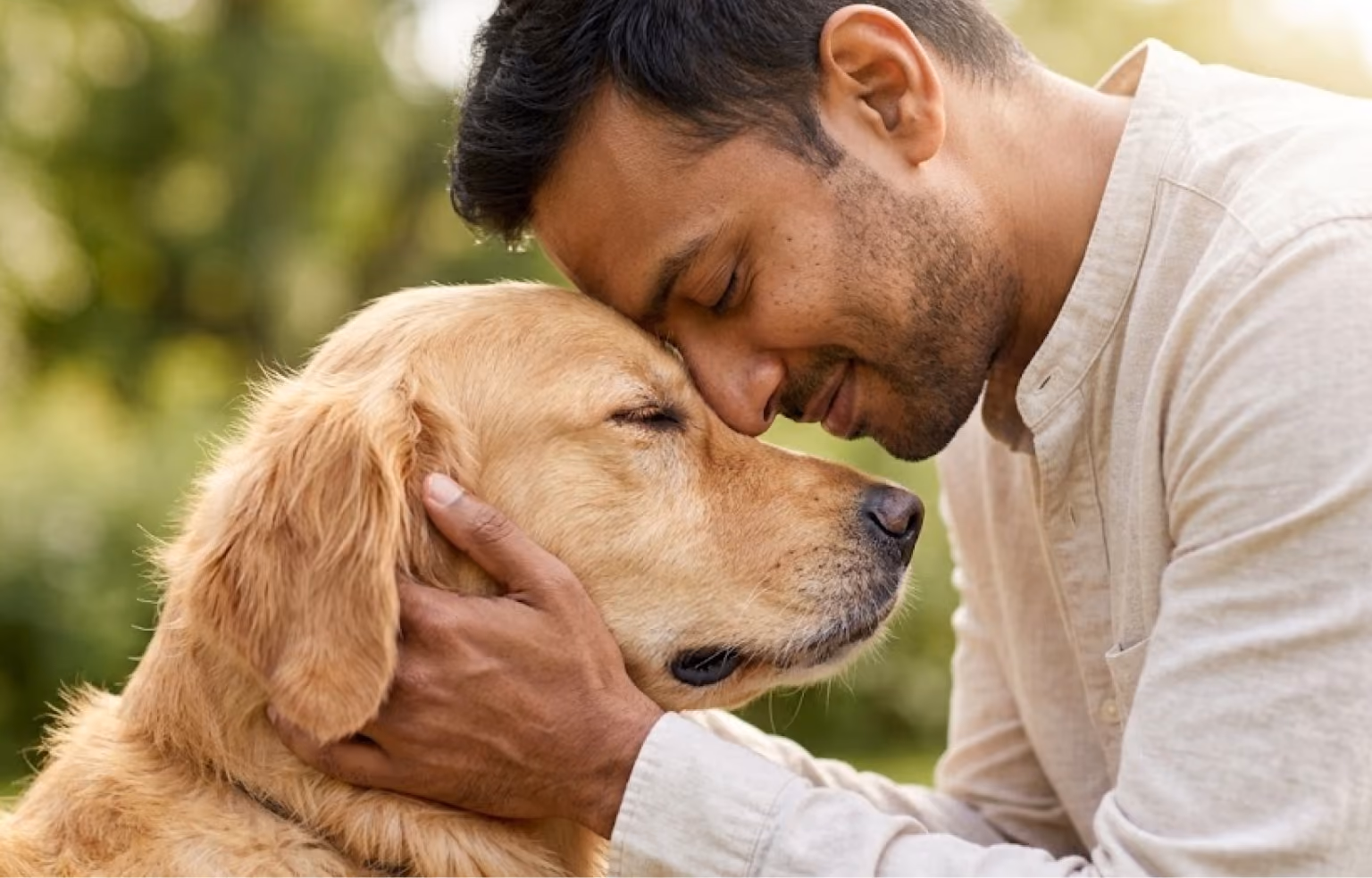 Man resting his face against a golden retriever's head