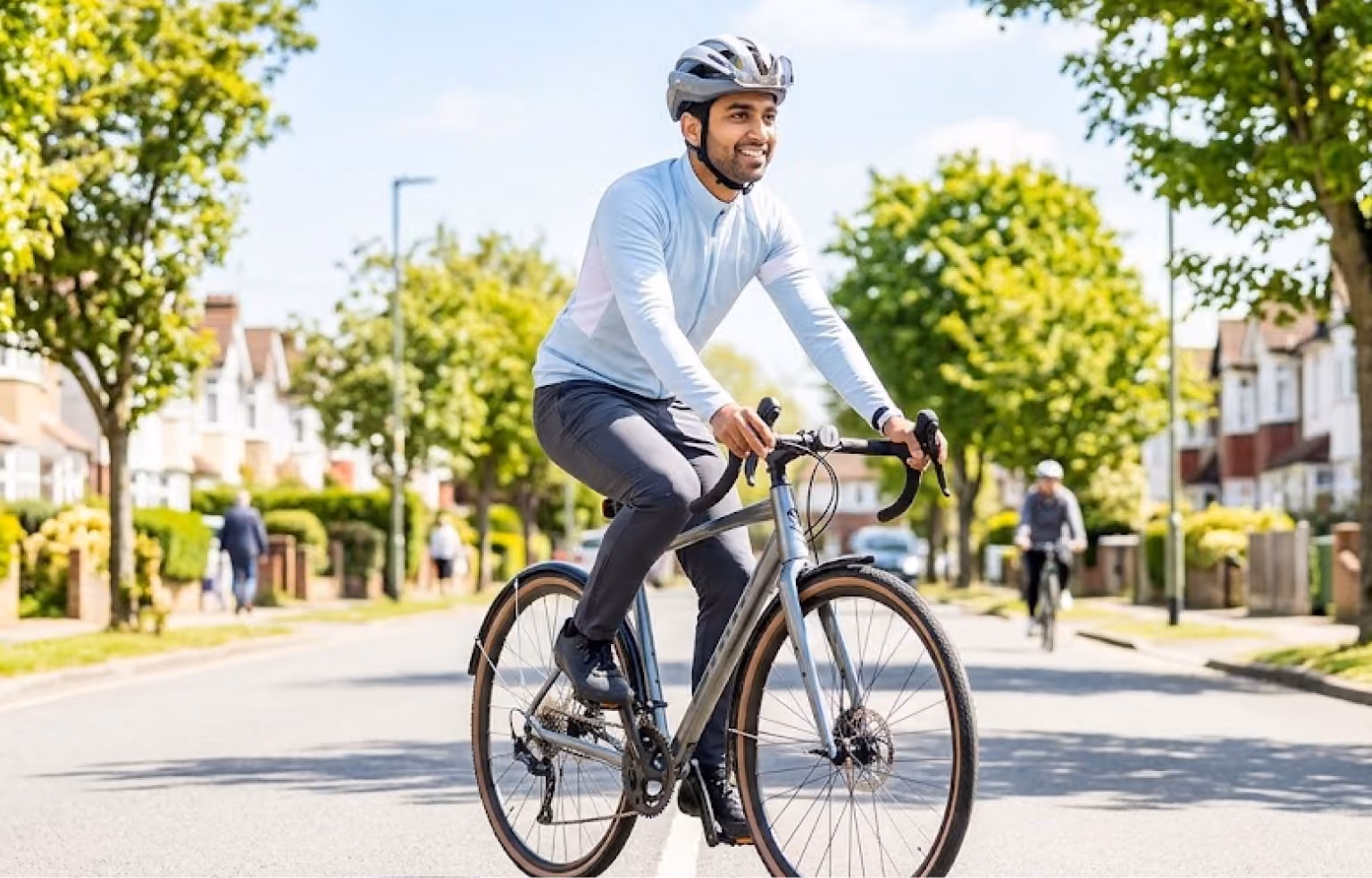 Man in a helmet riding a road bike along a tree-lined street