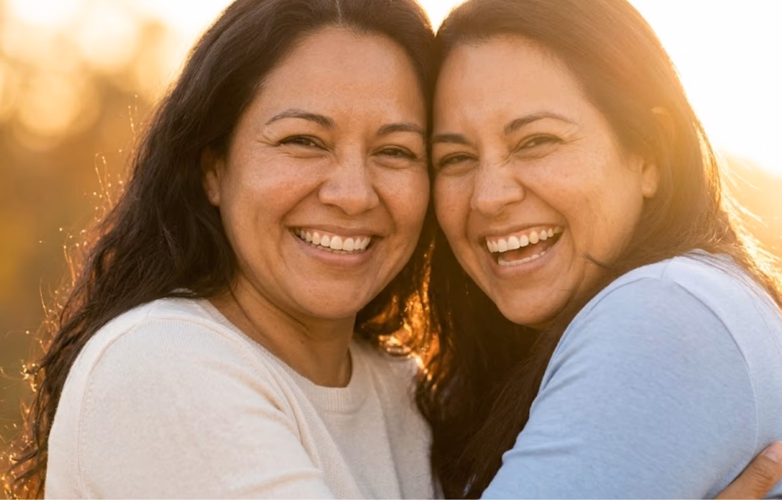 Two women smiling cheek to cheek in warm evening light
