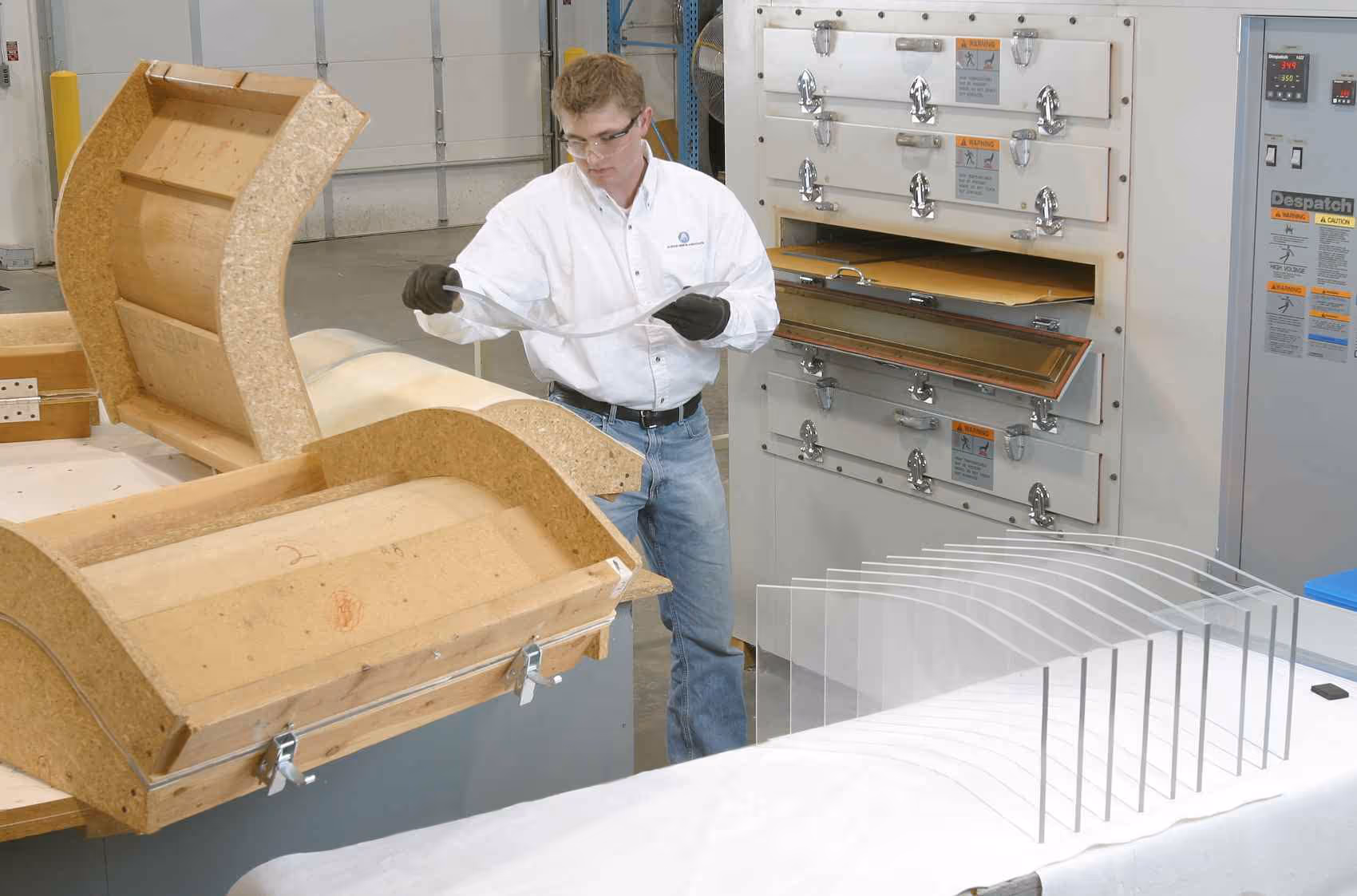 A man drape-forming a sheet of plastic over a form.