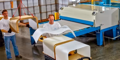 Two workers drape-forming a custom acrylic display