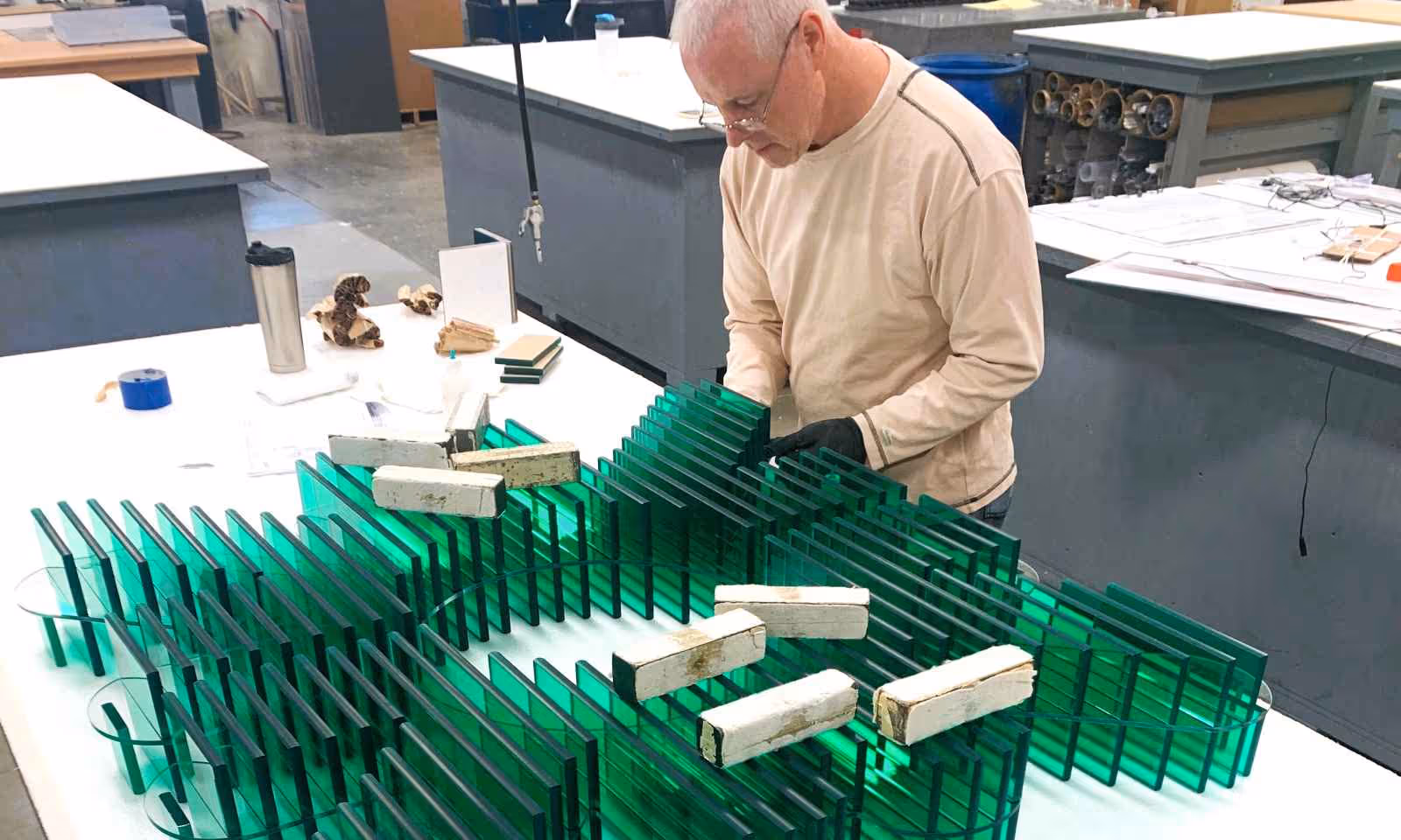 A worker assembling a prototype of a large illuminated custom sign using recycled acrylic