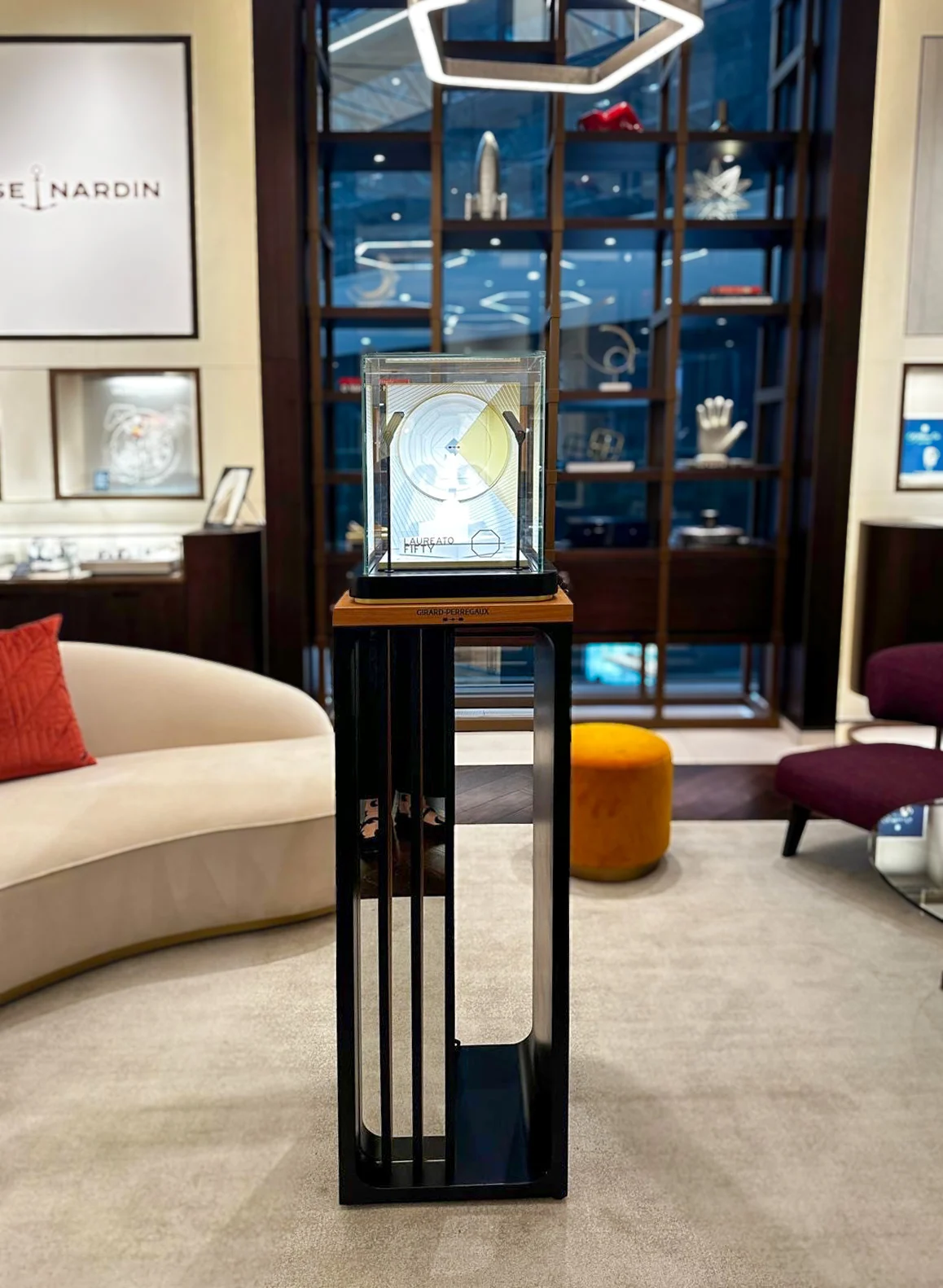 Chantecaille makeup products including tubes, jars, lipsticks, and a brush on a clear display stand.