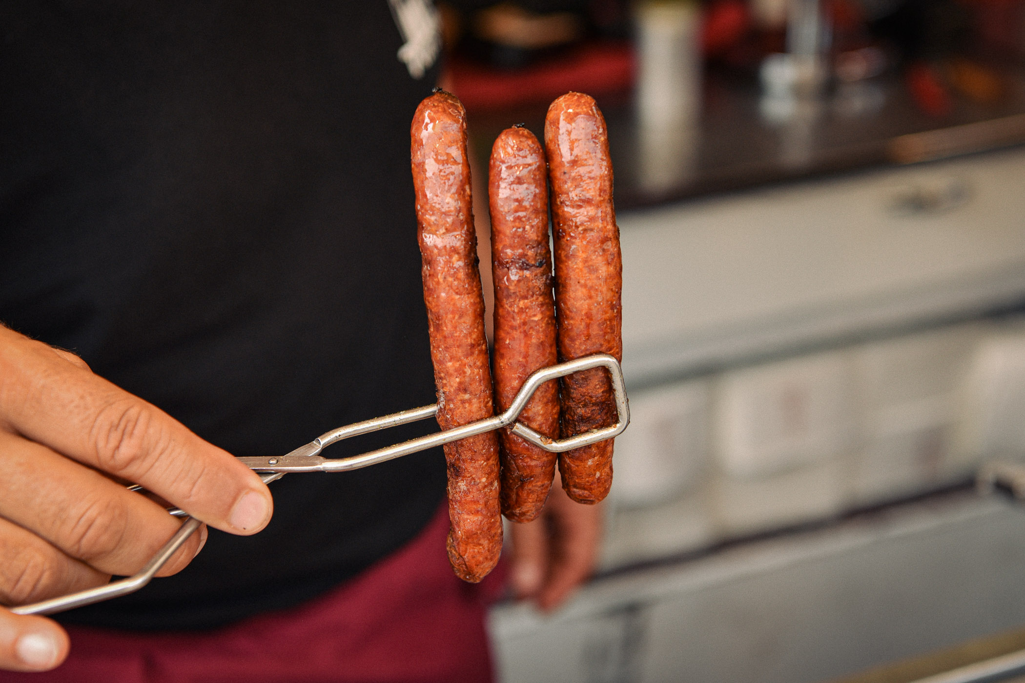 Drei gegrillte Würste in Zange