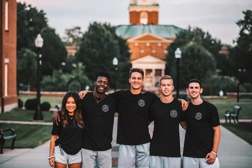 Five Storage Scholars student movers in matching black shirts standing together on a college campus