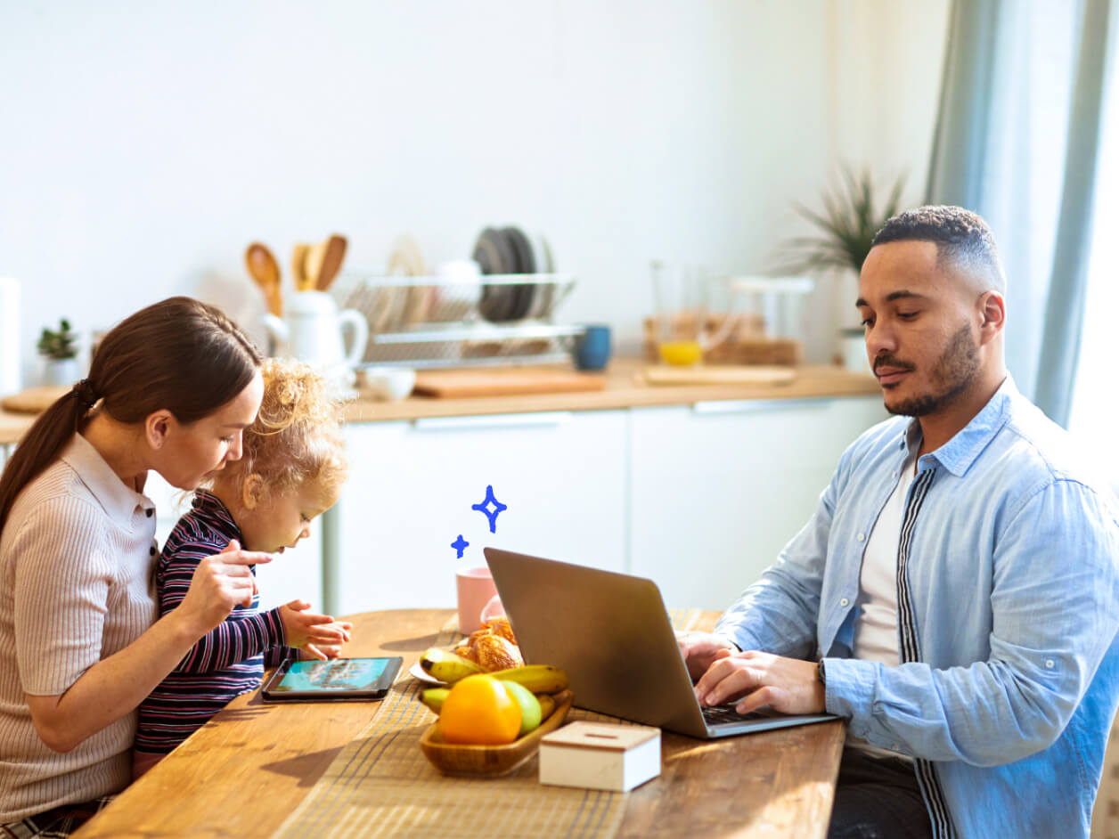 A family enjoying time together in the kitchen: one adult uses a laptop.