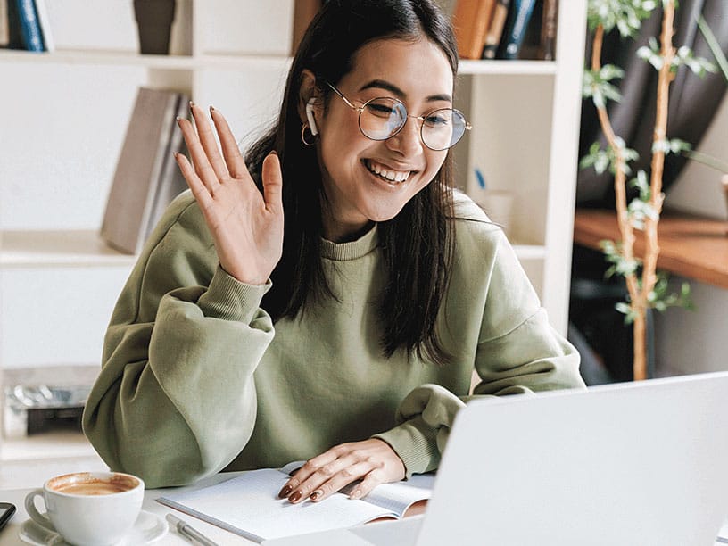 Woman waving at computer screen