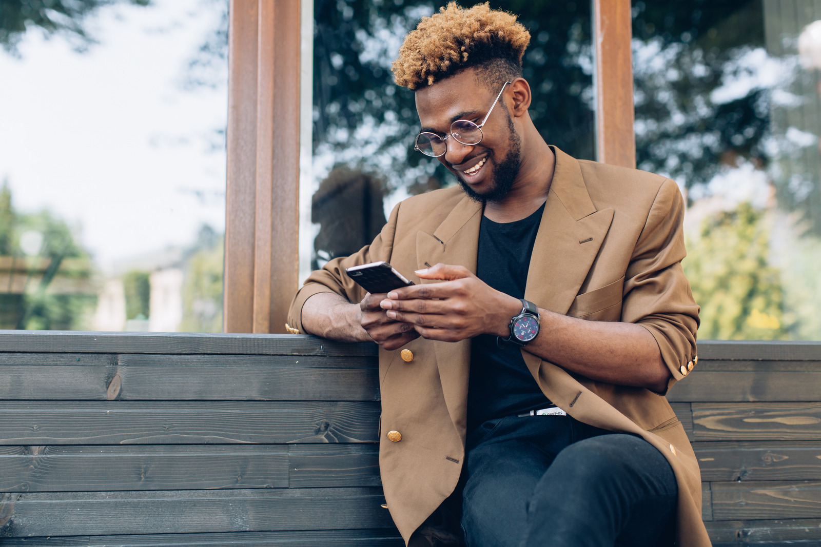A man on his phone sitting on a bench.