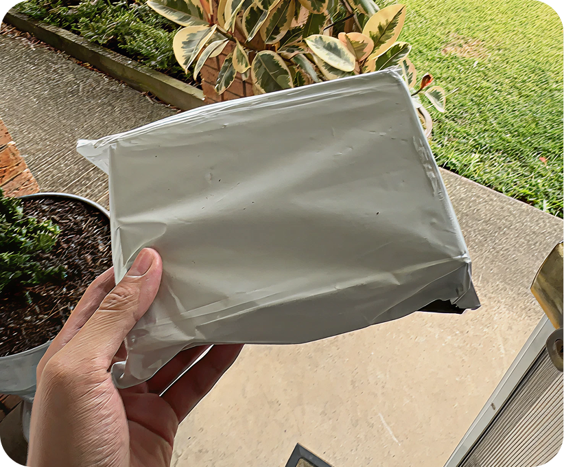 A man at his front door holding a discreet, unmarked package containing Pilot's hair loss treatment