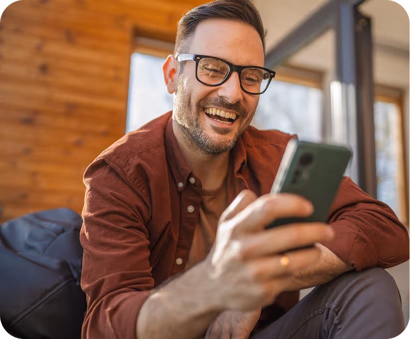 Man looks happy as he uses his phone to order hair loss treatment