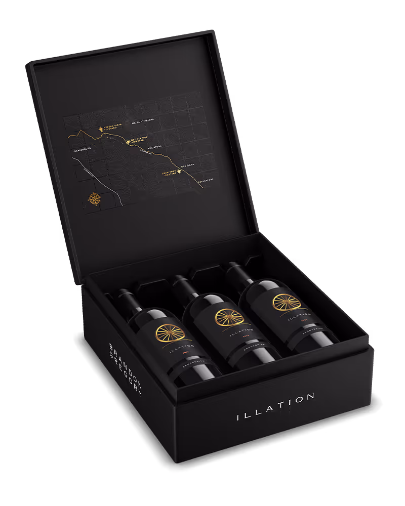 Open black box with three bottles of Illation wine inside and a gold map printed on the inside lid.