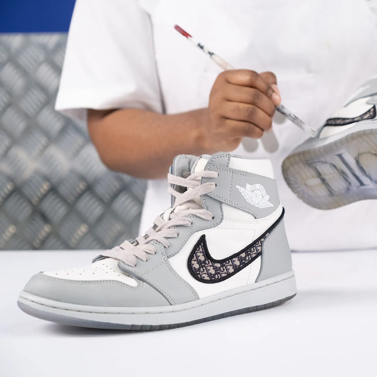 a person holding a paintbrush and a grey and white sneaker