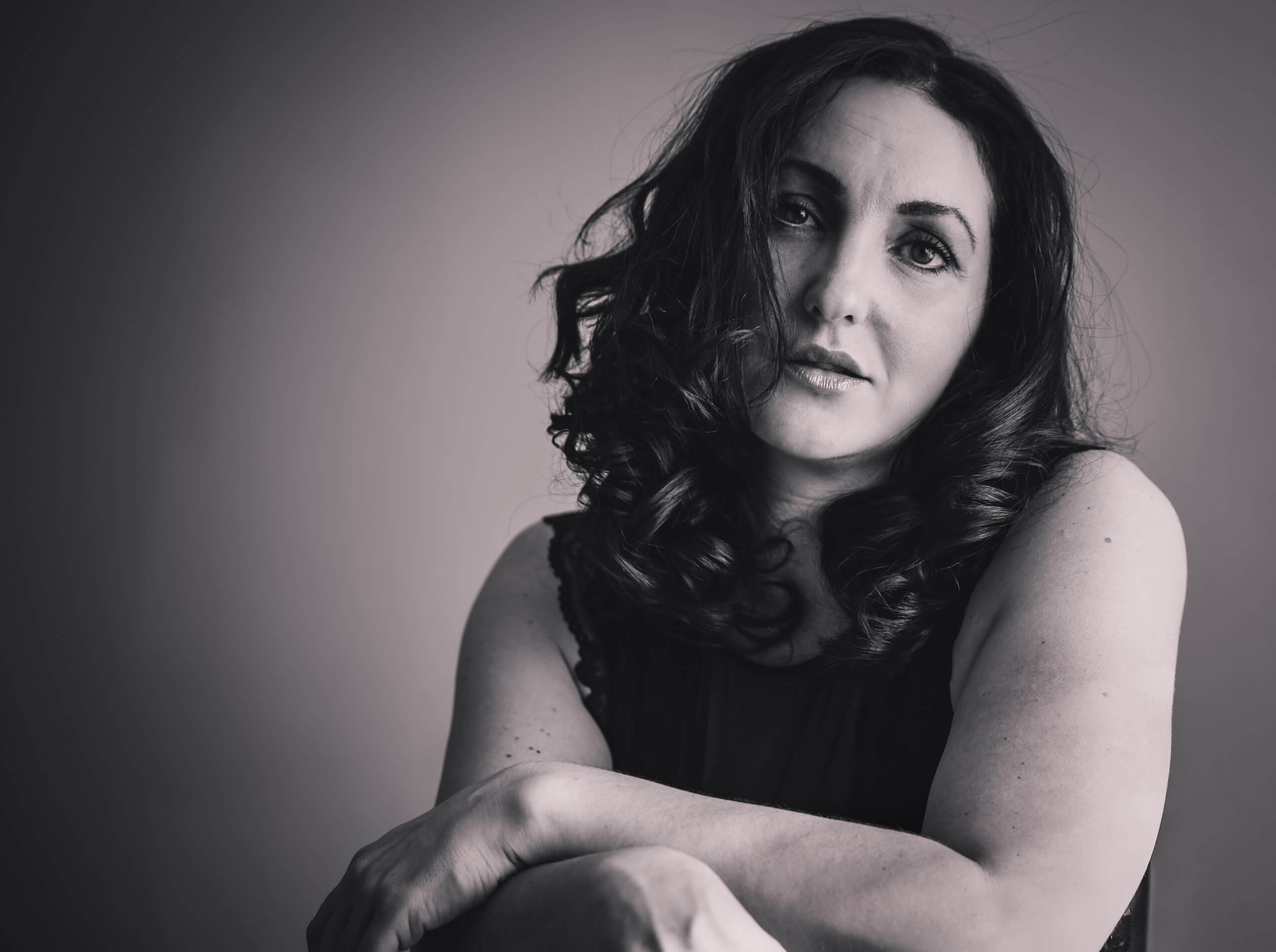 A woman sits with her arms crossed.