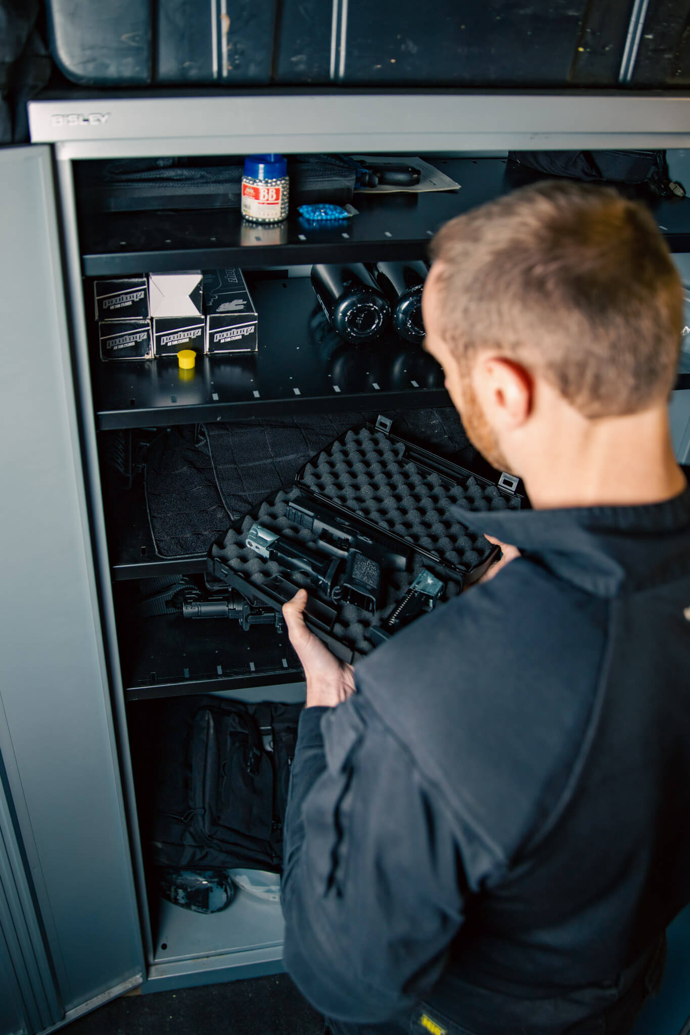 A man opens a plastic case to reveal a pistol and it's ancillaries. 
