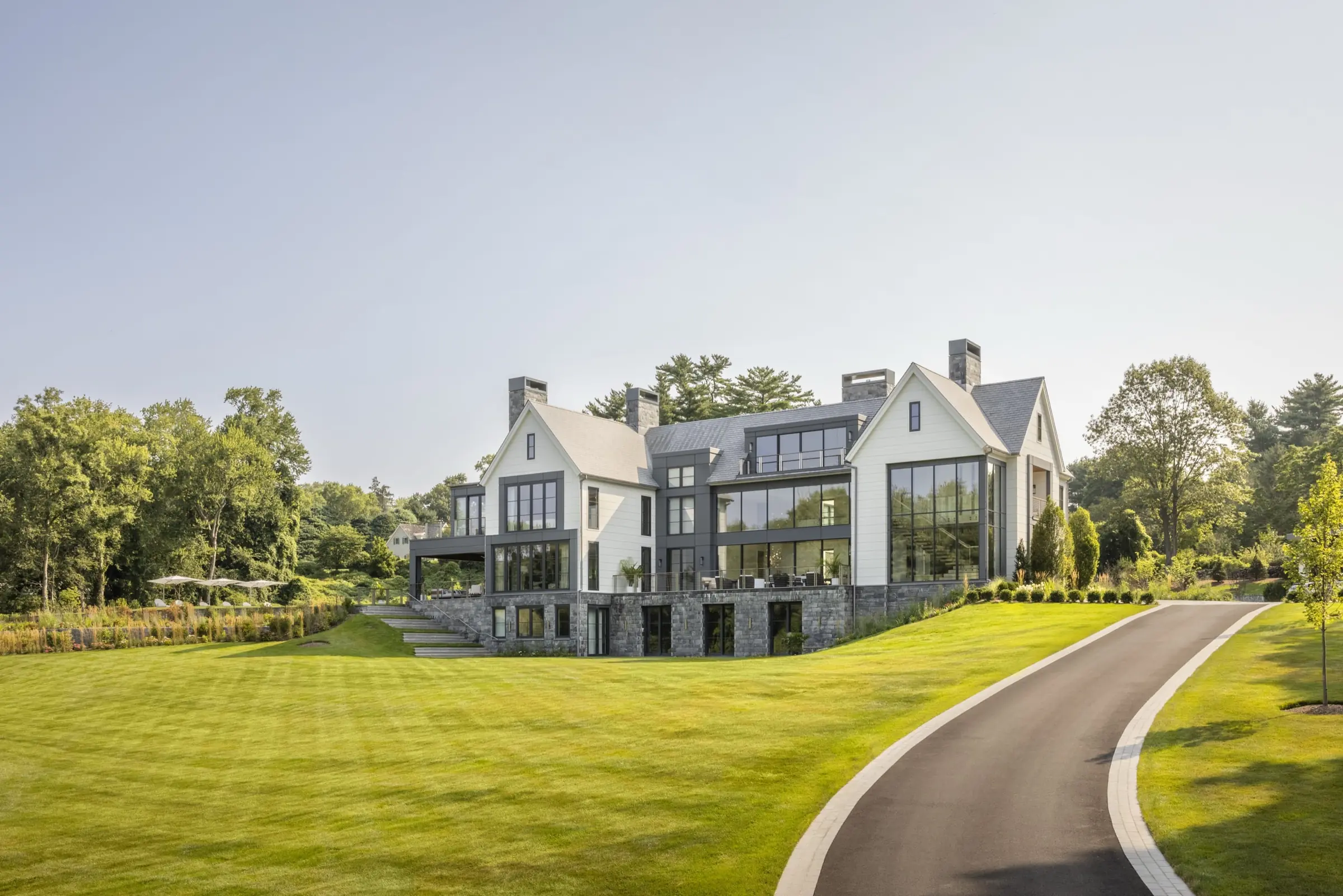 Modern farmhouse-style estate exterior with stone base and expansive lawn in Fairfield County, Connecticut