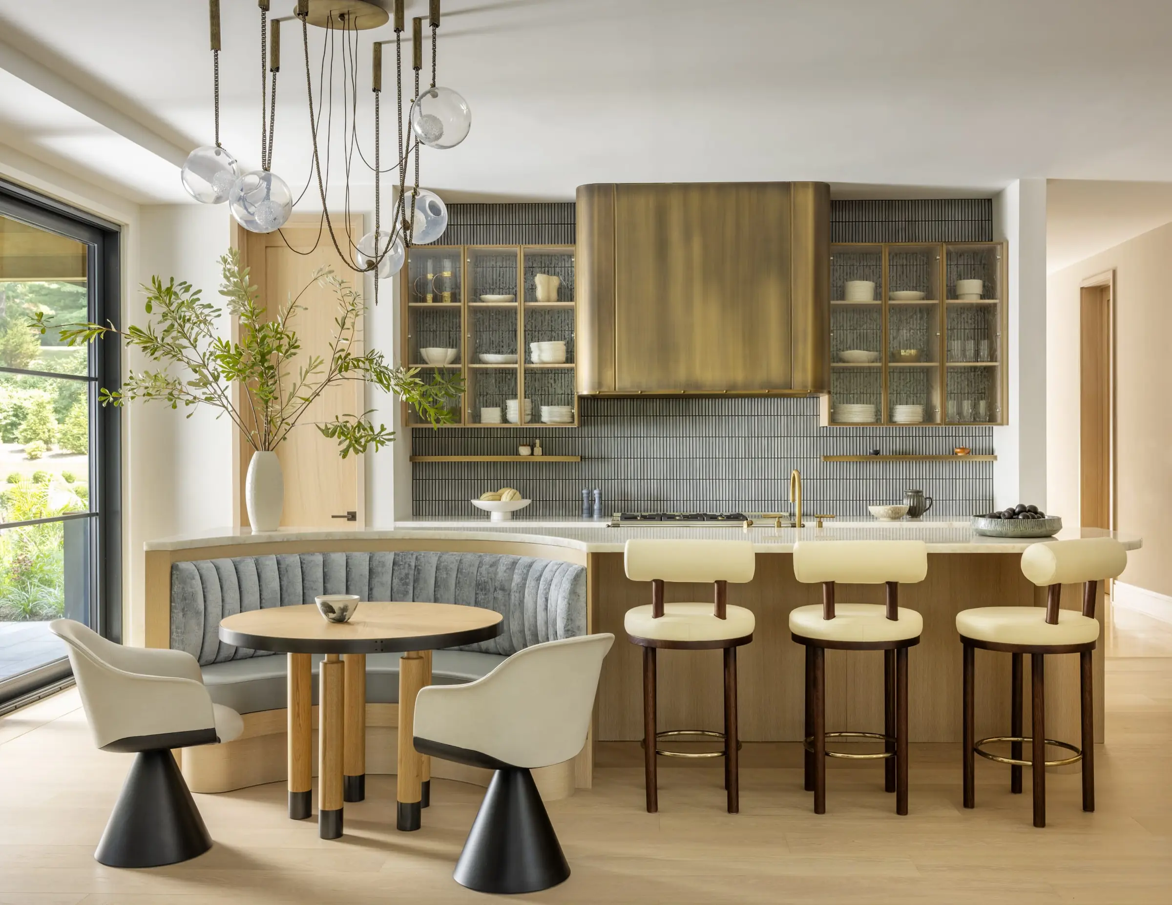 Kitchen with curved banquette seating, brass range hood, and bar stools