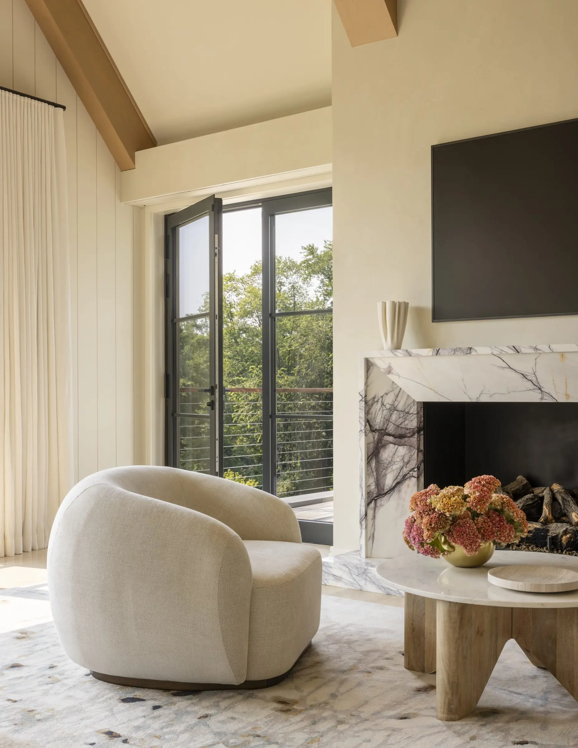 Living room seating nook beside a marble fireplace with floor-to-ceiling windows