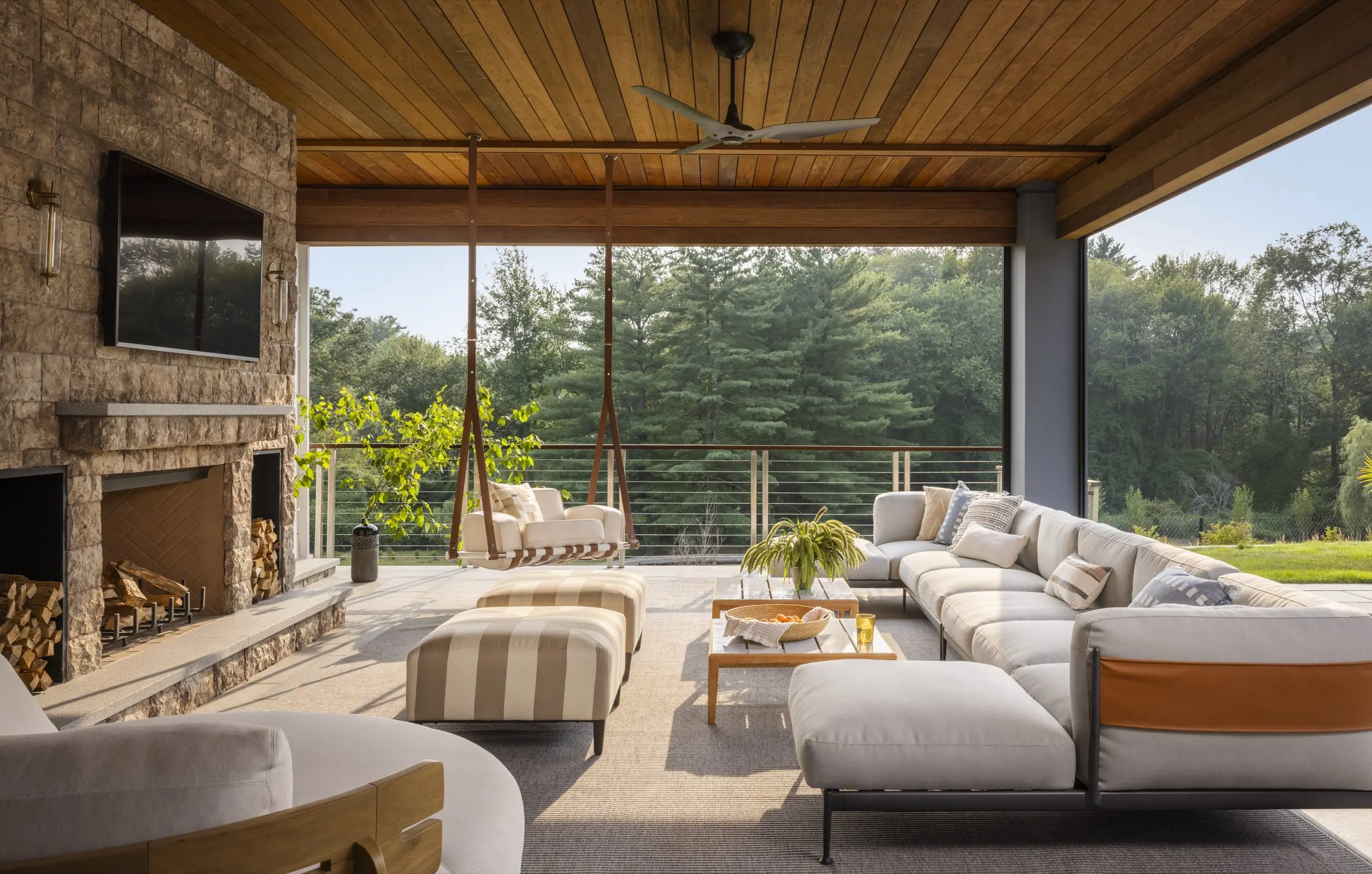Screened outdoor living room with stone fireplace and wood ceiling
