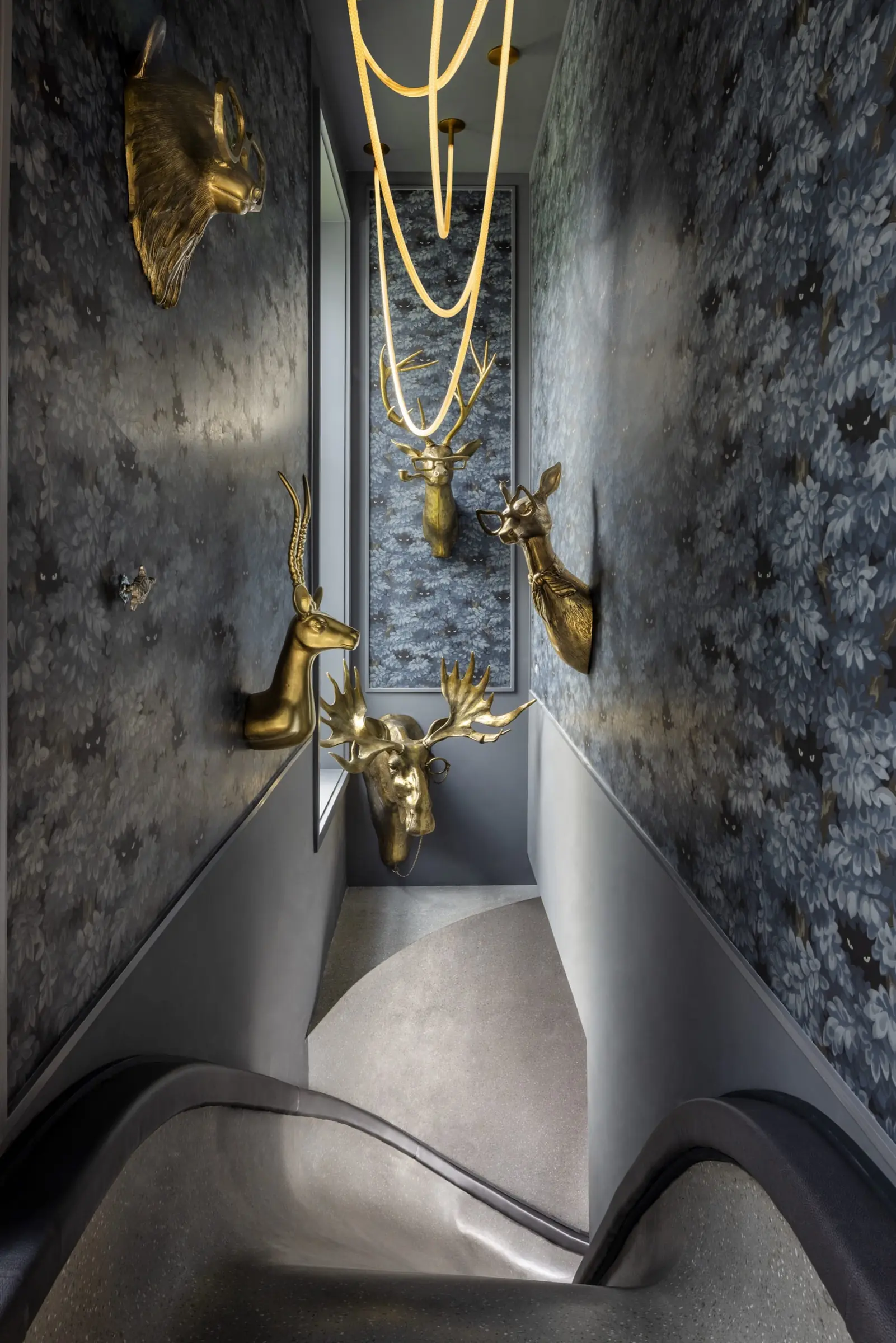 Hidden speakeasy entrance with brass animal head sculptures on textured wallpaper