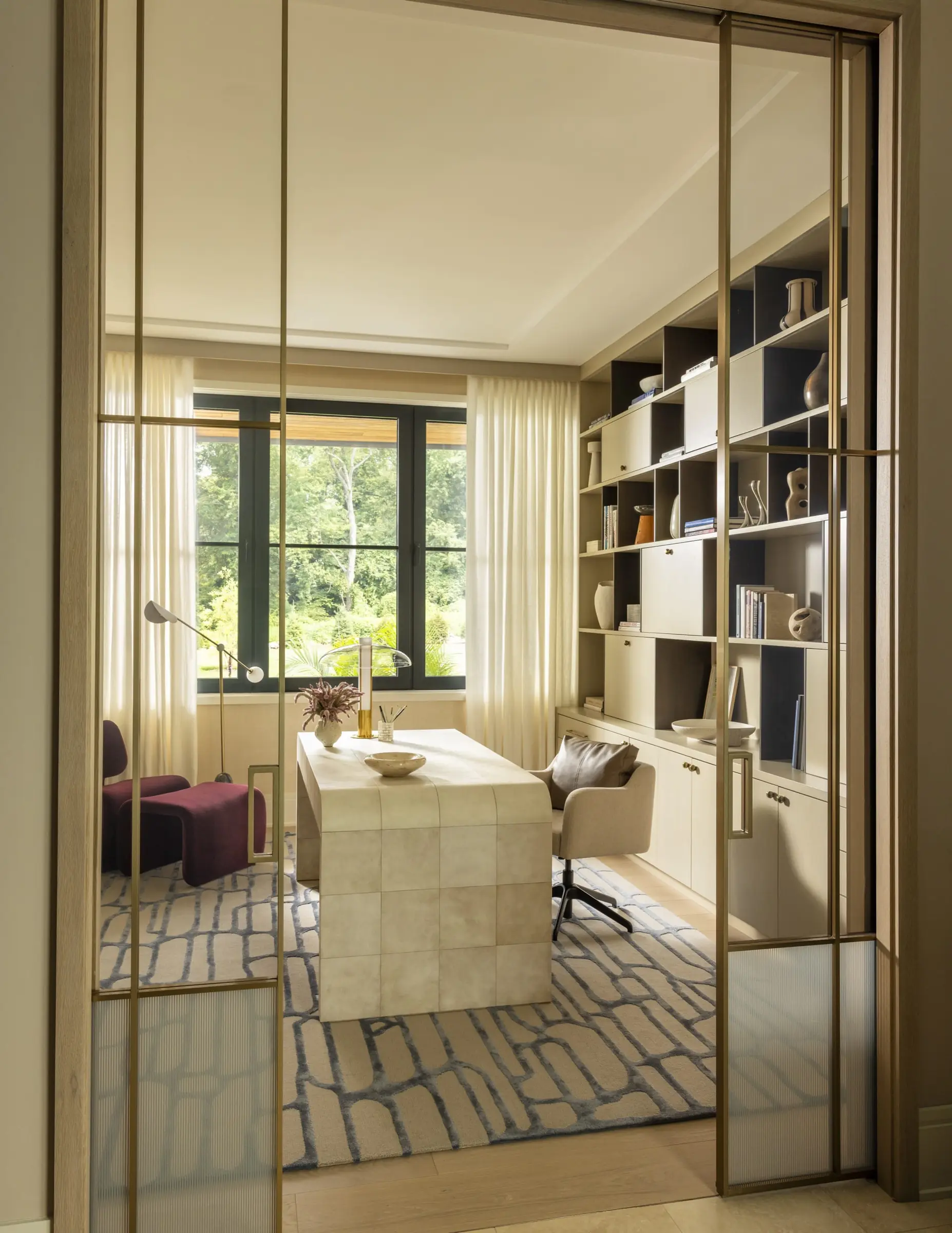 Home office with sliding glass doors and floor-to-ceiling built-in shelving