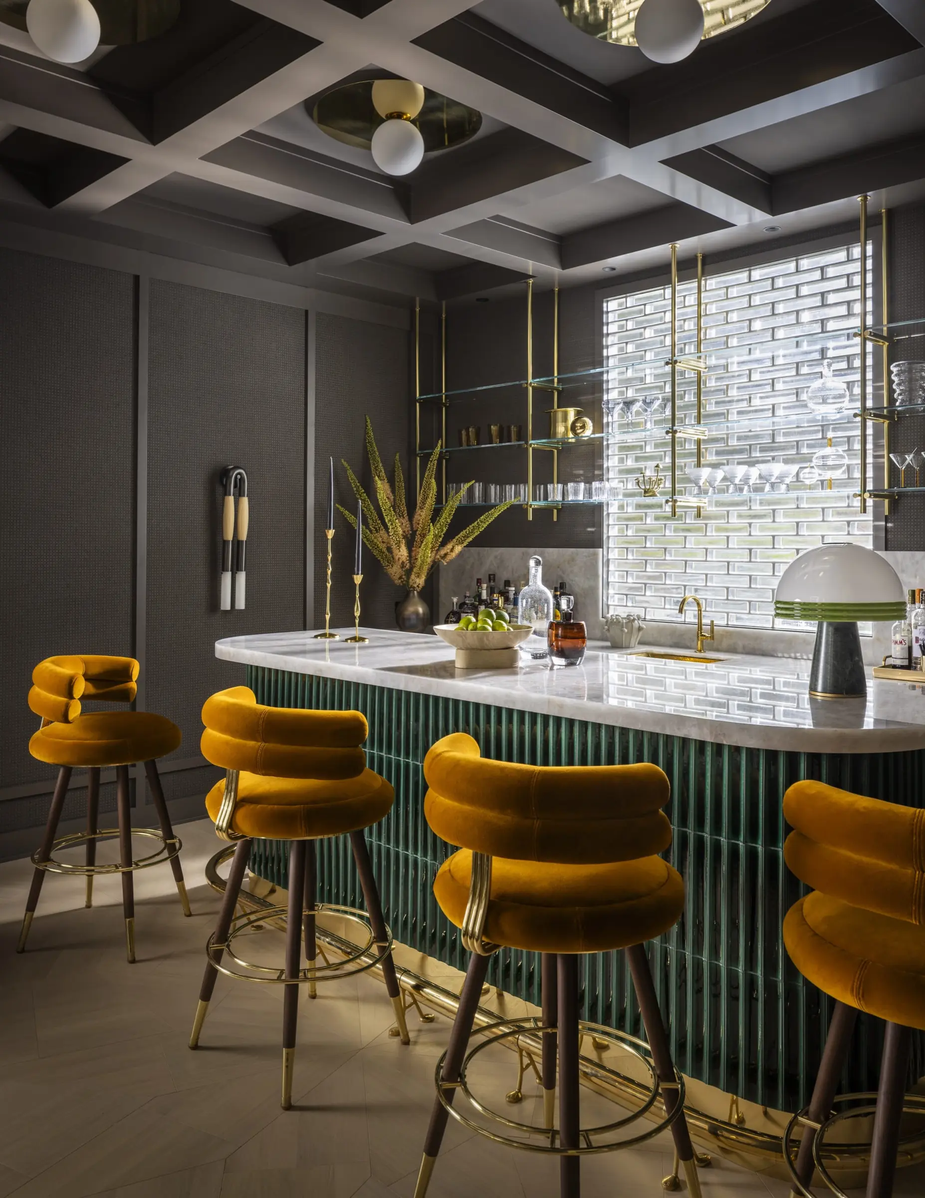 Lower-level bar with green cabinetry, marble counter, and brass barstools