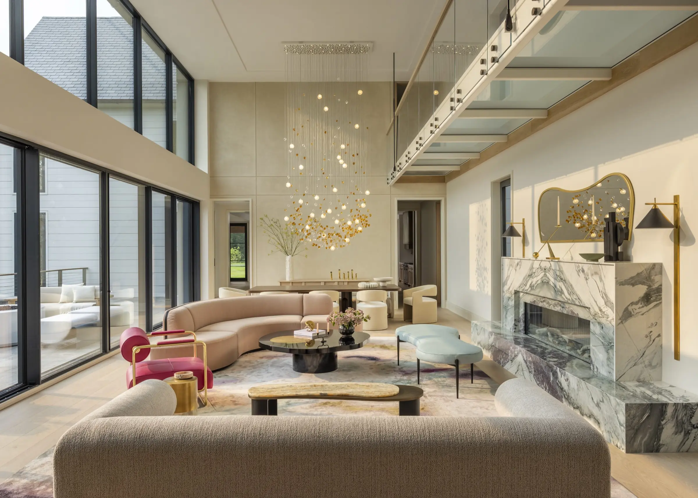 Great room with curved sofas, glass orb chandelier, and marble fireplace, designed by one of the best interior designers in New York
