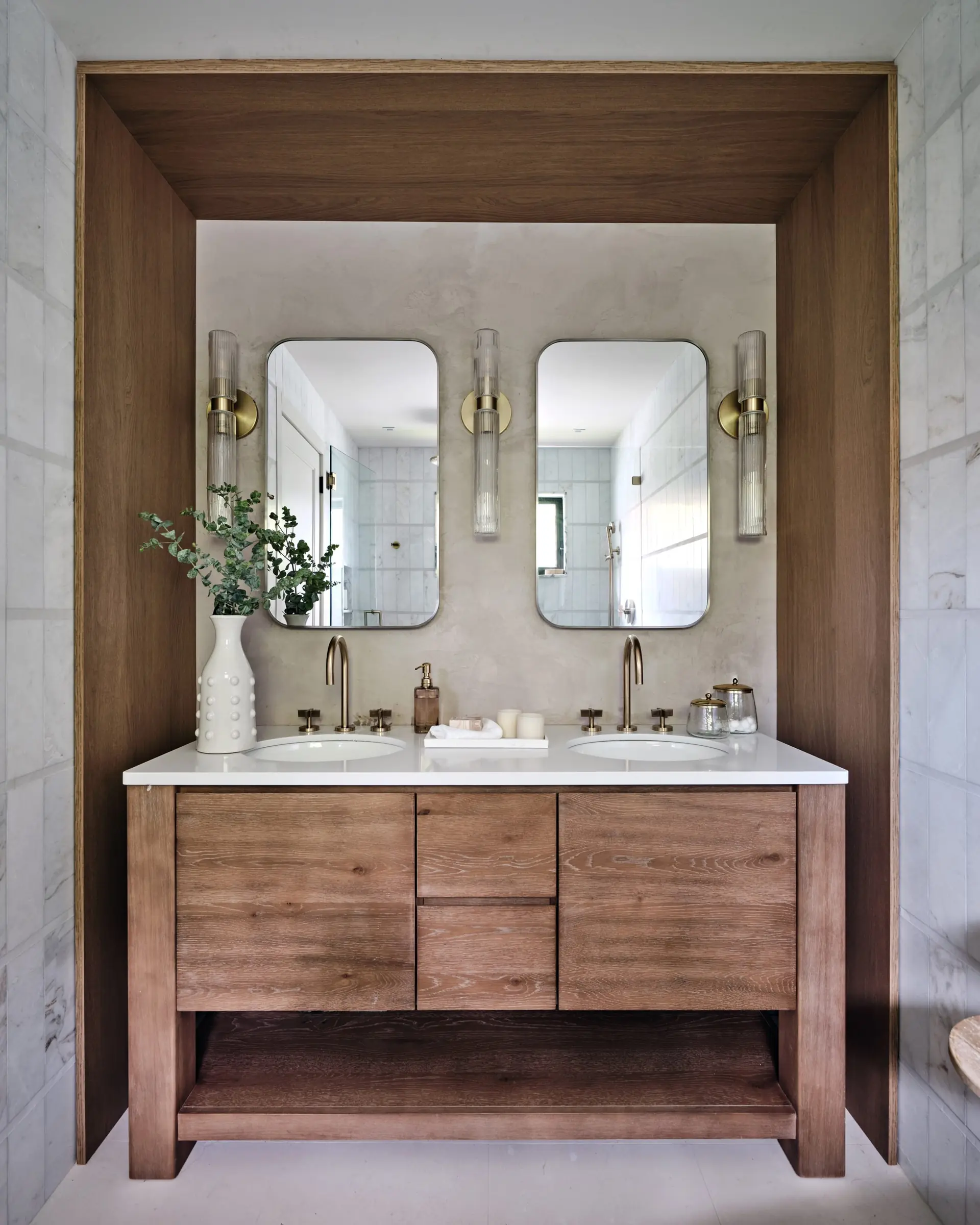 Bathroom with wood-enclosed double vanity and natural stone walls