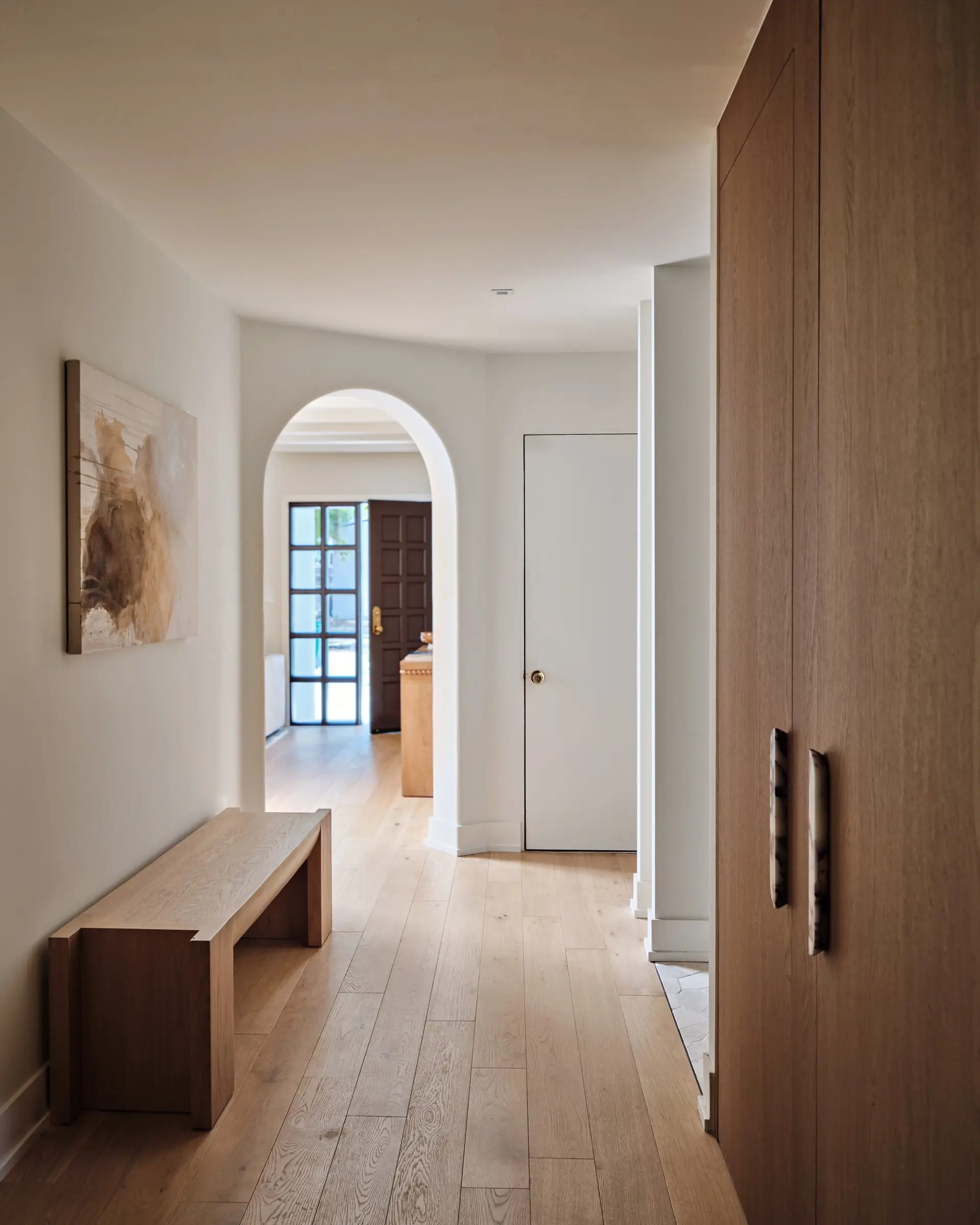 Hallway with built-in wood bench atop wide-plank oak floors
