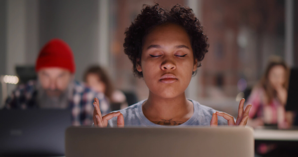 Productive things to do when bored: person meditating in front of a laptop