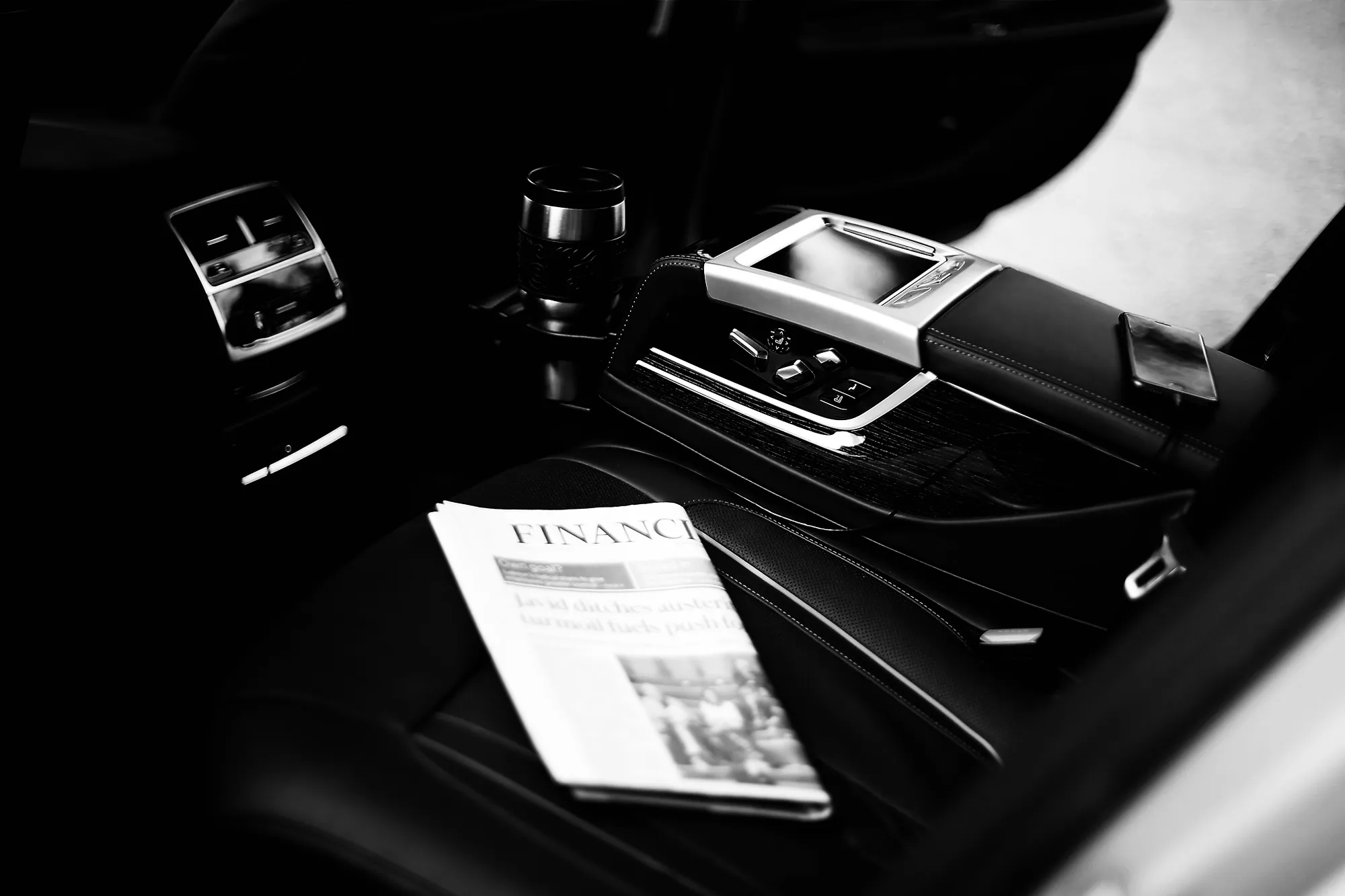 A folded newspaper on the rear seat of a chauffeur-driven car