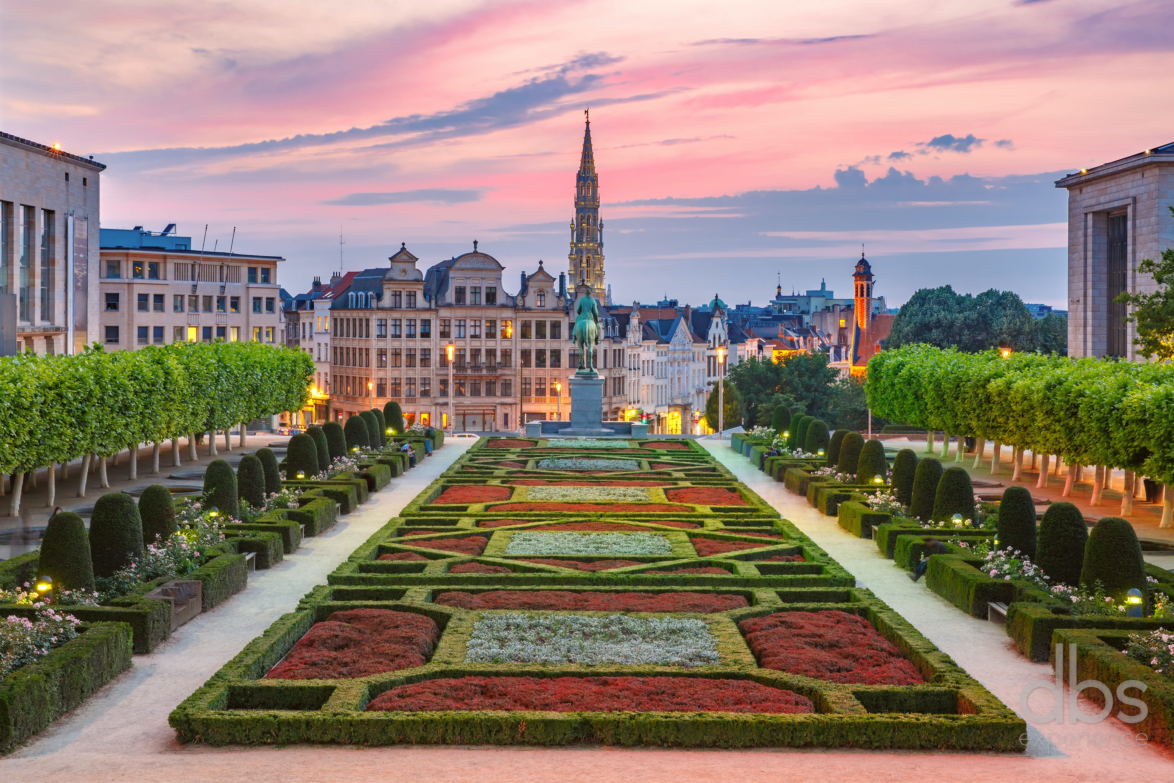 Formal gardens of the Mont des Arts in Brussels at sunset, with the Town Hall spire behind