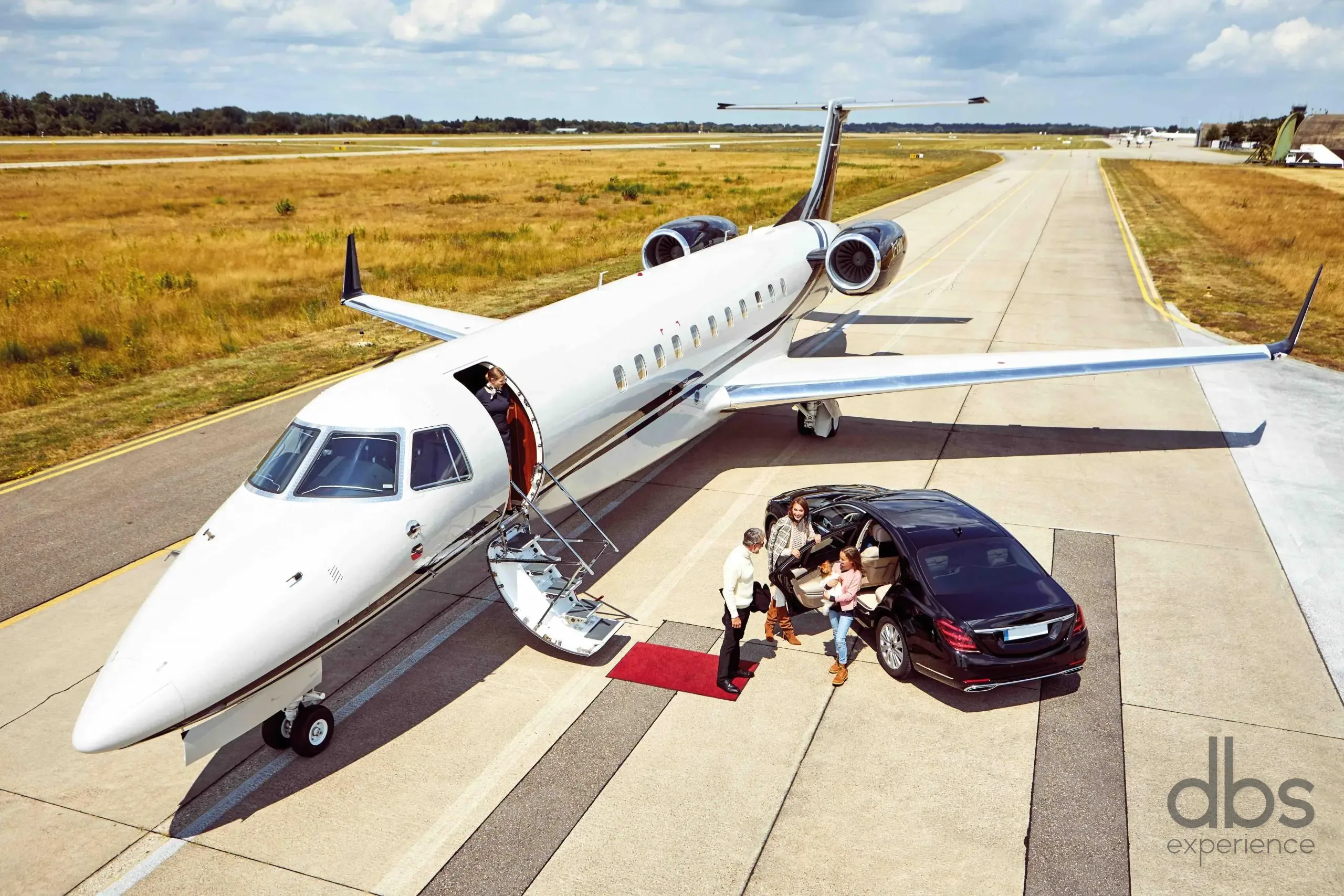 A DBS EXPERIENCE chauffeur welcoming guests beside a private jet
