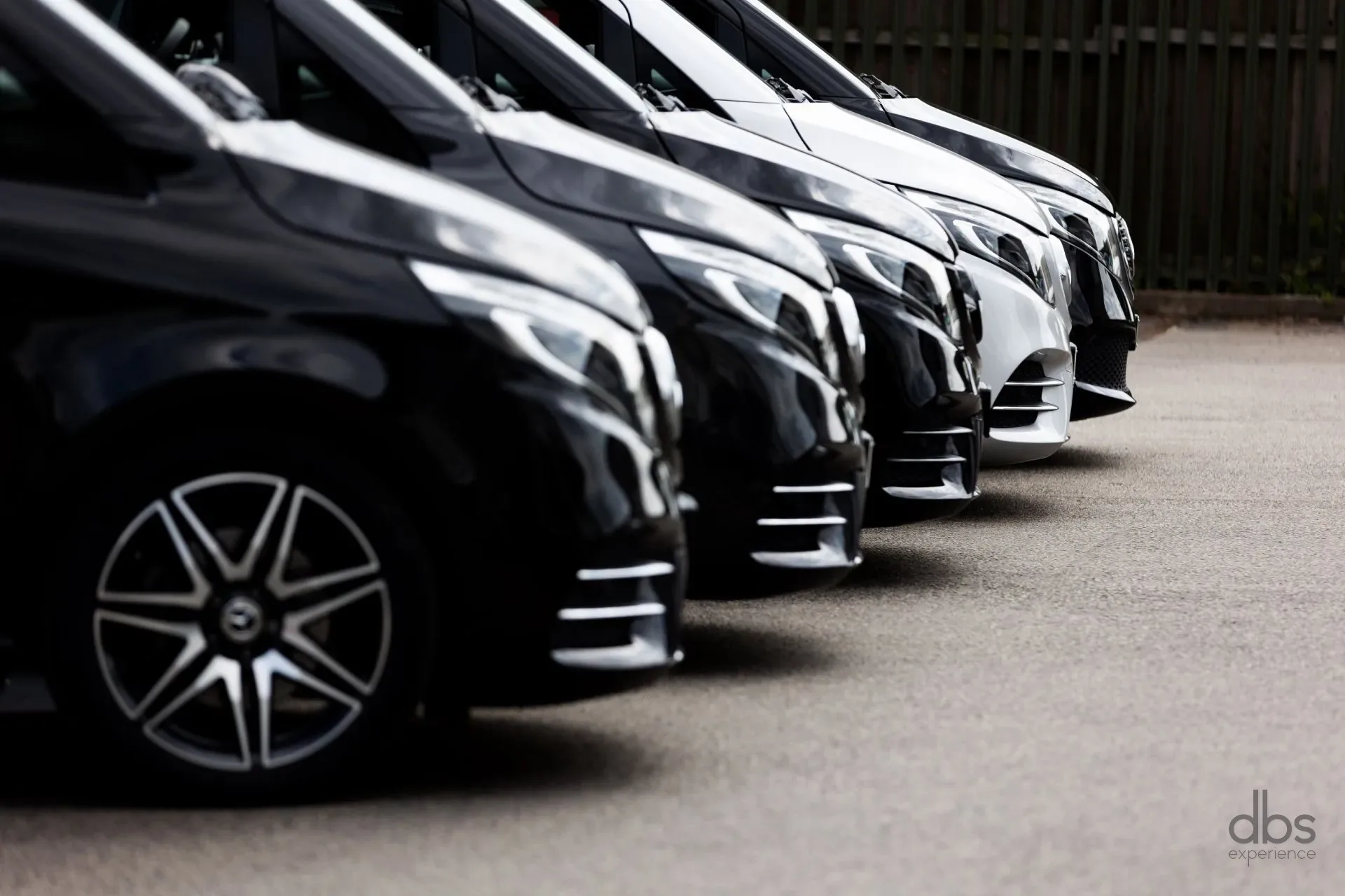 A row of black Mercedes-Benz V-Class vans, the DBS EXPERIENCE Executive Van fleet in Paris
