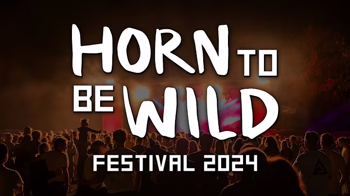Thumbnail des Horn to be Wild Festival 2024 Aftermovie. Es ist groß das Logo "Horn to be Wild Festival 2024" im Vordergrund in weiß. Im Hintergrund ist eine Menschenmasse vor der Bühne zu sehen. Auf dem Bild ist es schon dunkel und die Szenerie ist von Lichtern und Scheinwerfern erleuchtet.