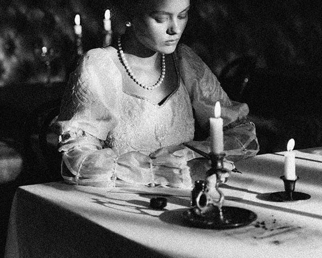 Girl writing a letter by candle light.