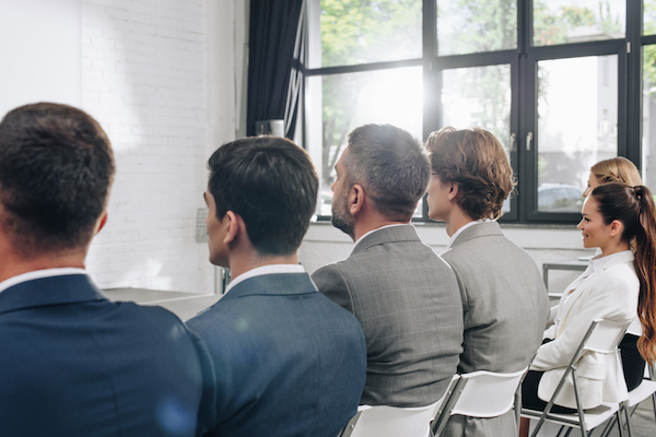 rear view of businesspeople sitting on chairs during training in hub
