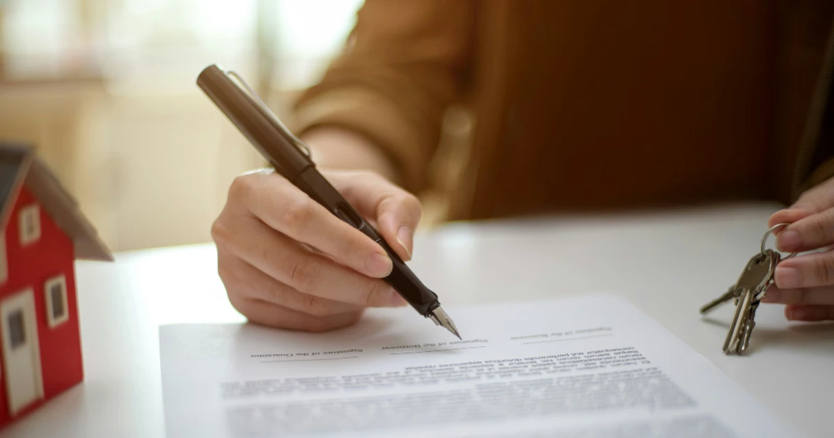Concept of someone filling out an umbrella insurance policy on a table next to a home
